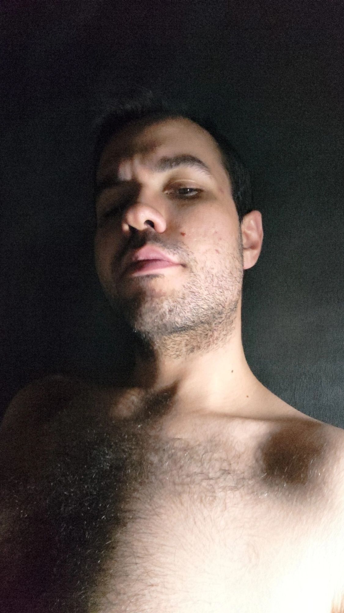 Selfie minha, um homem branco com barba por fazer, metade do meu rosto está iluminada, a outra metade está na sombra.