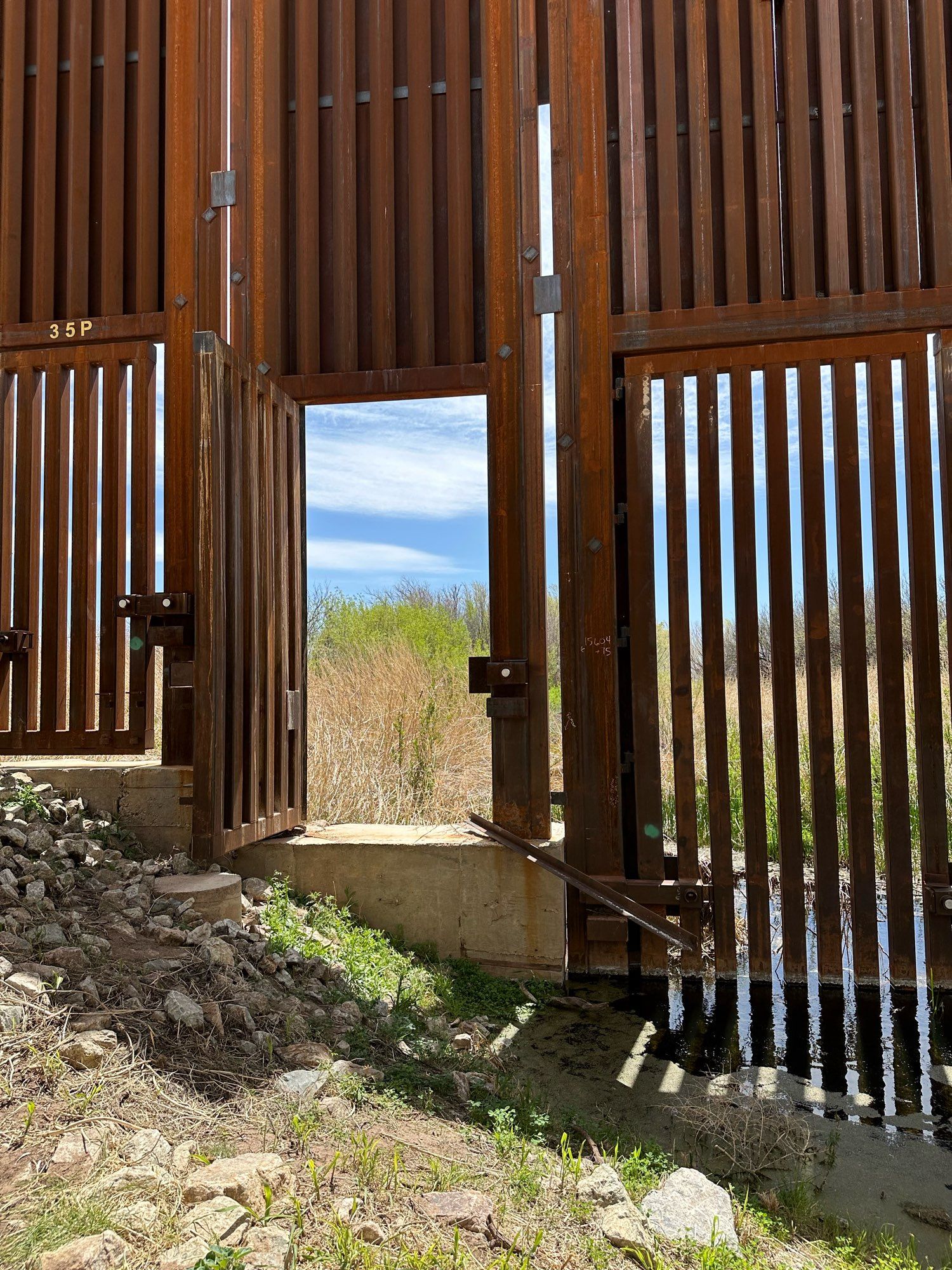 Border wall at Blackwater draw in Arizona with barbed wire strung across the lone wildlife opening