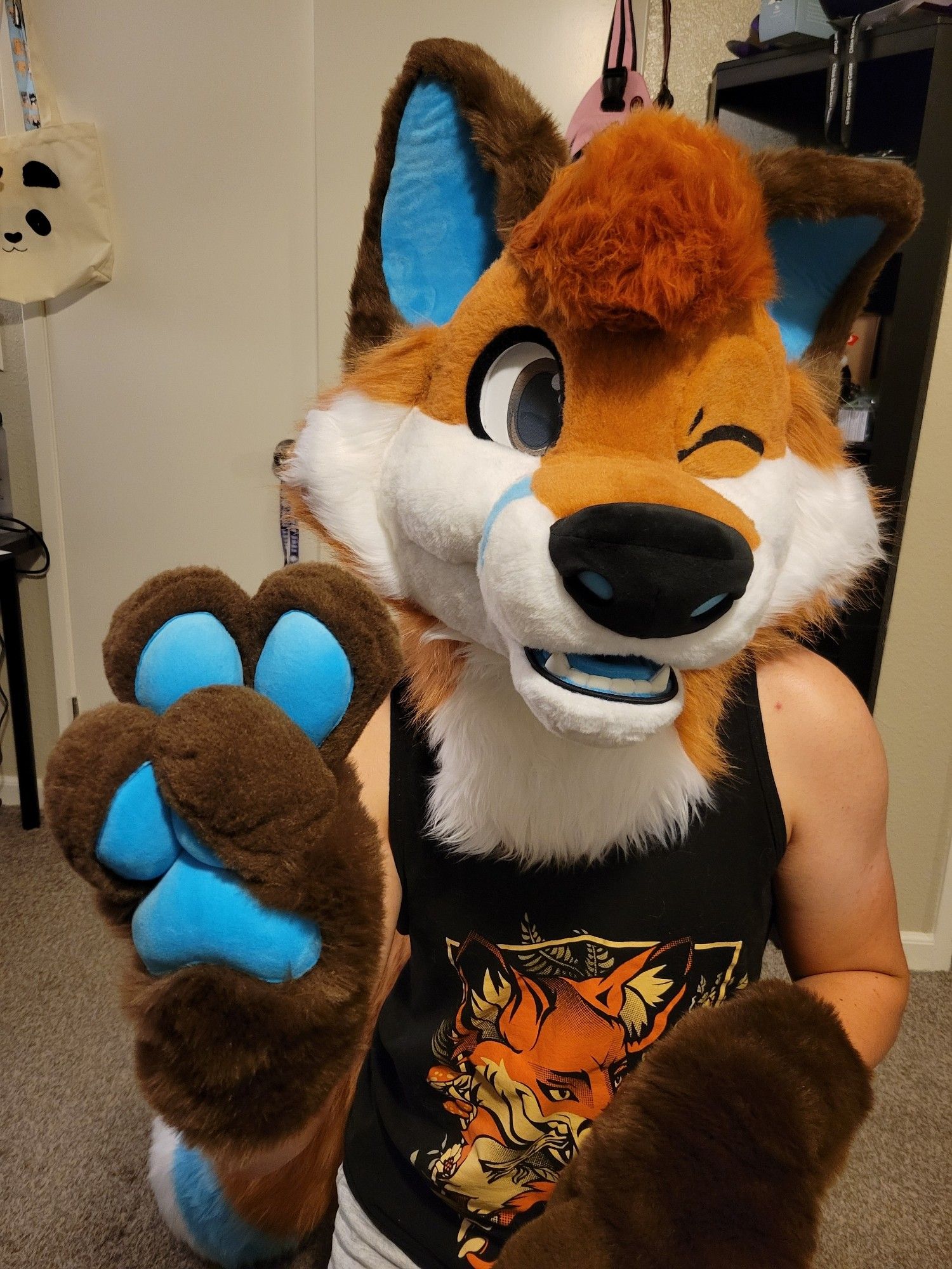 Fox fursuiter winking and holding a peace sign