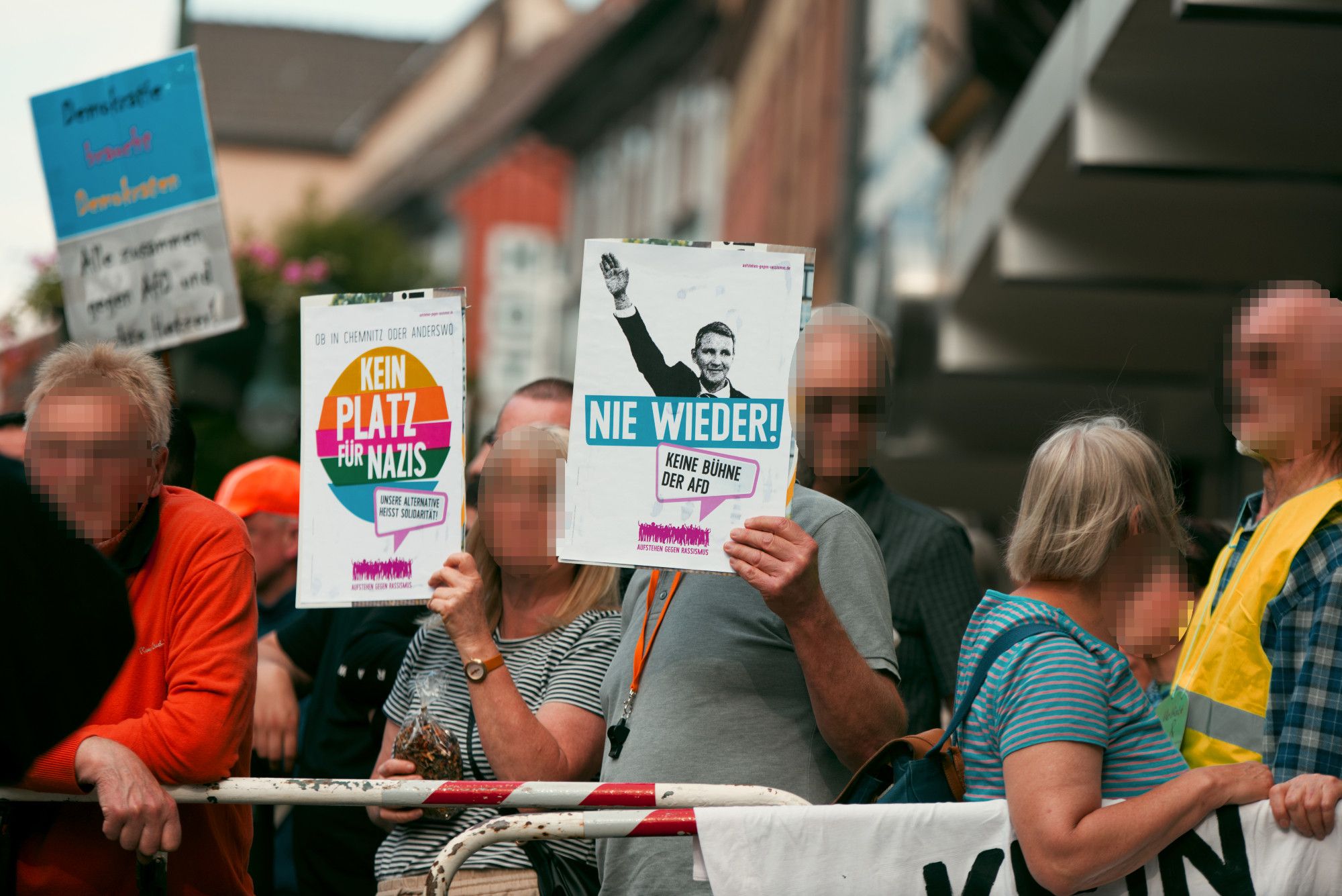 Zwei weiße Pappschilder mit Parolen gegen die AfD, die vom Gegenprotest hochgehalten werden