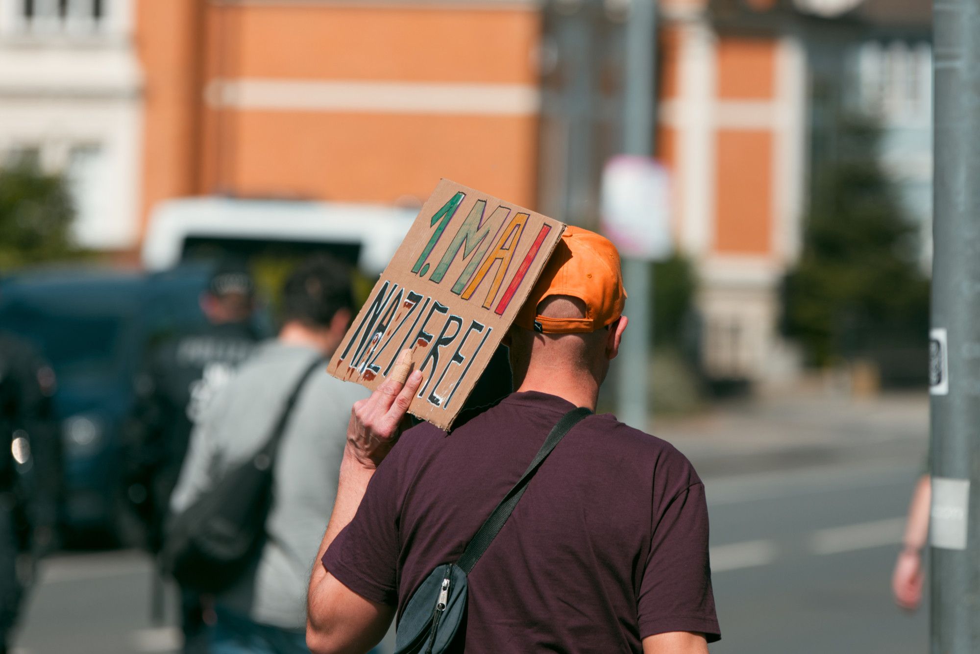 Eine Person direkt am Rande der rechten Demoroute mit einem bunten "1. Mai nazifrei" Pappschild