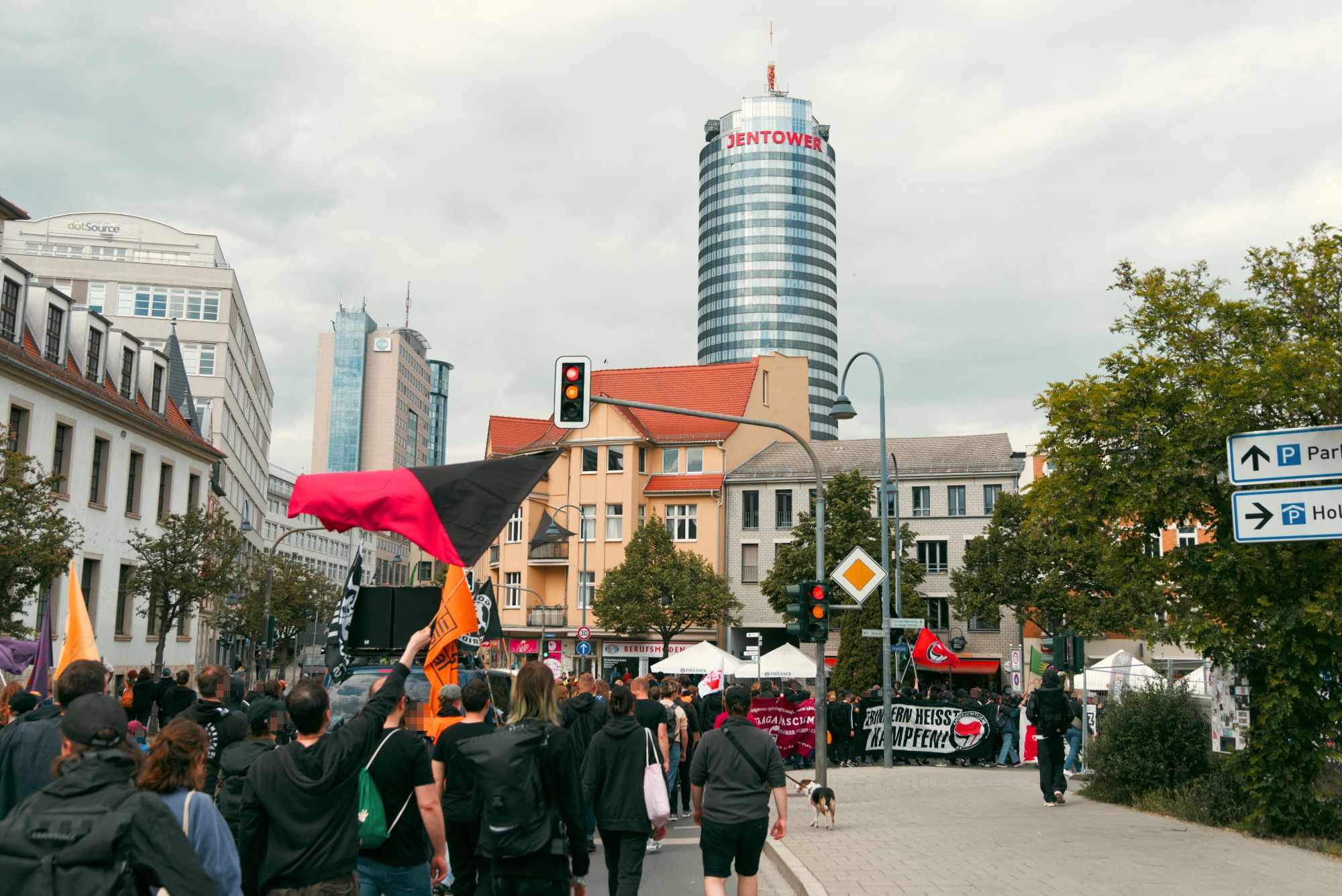 Blick über den Demonstrationszug, der an einer Kreuzung nahe der Innenstadt rechts abbiegt. Im Hintergrund die Skyline von Jena