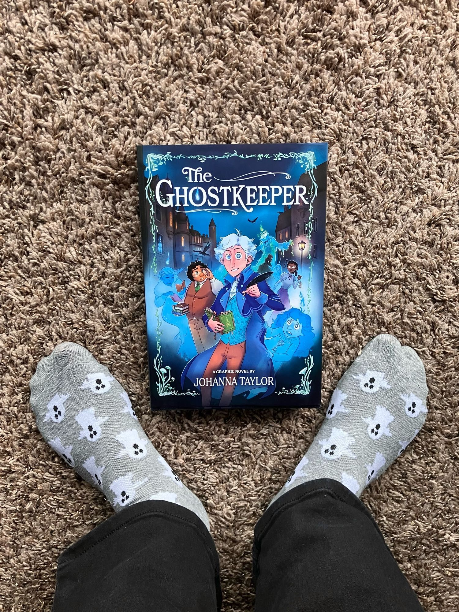 Shot of my feet wearing ghost socks standing over a copy of my book