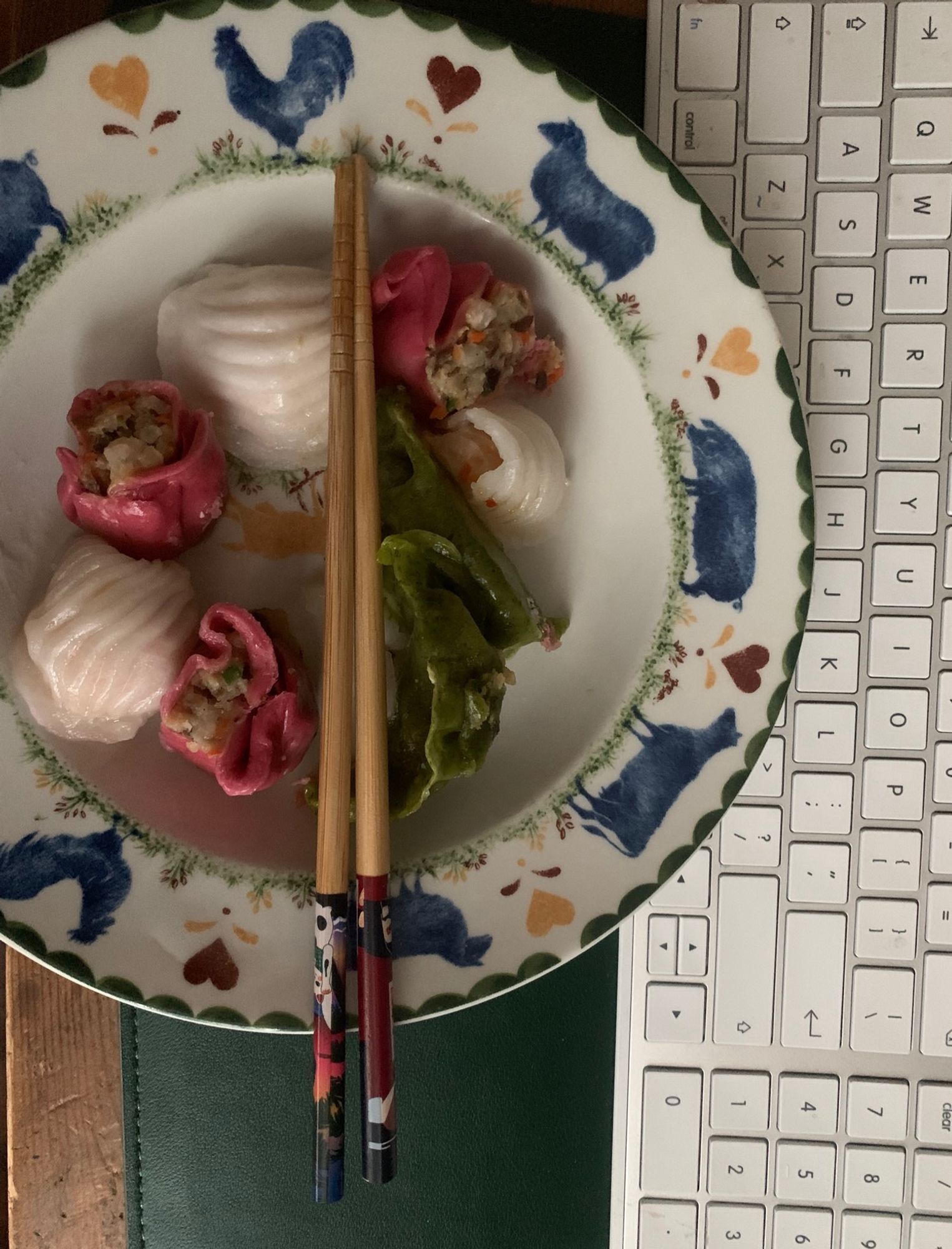 A photo of a bowl of dim sum with chopsticks beside a computer keyboard 