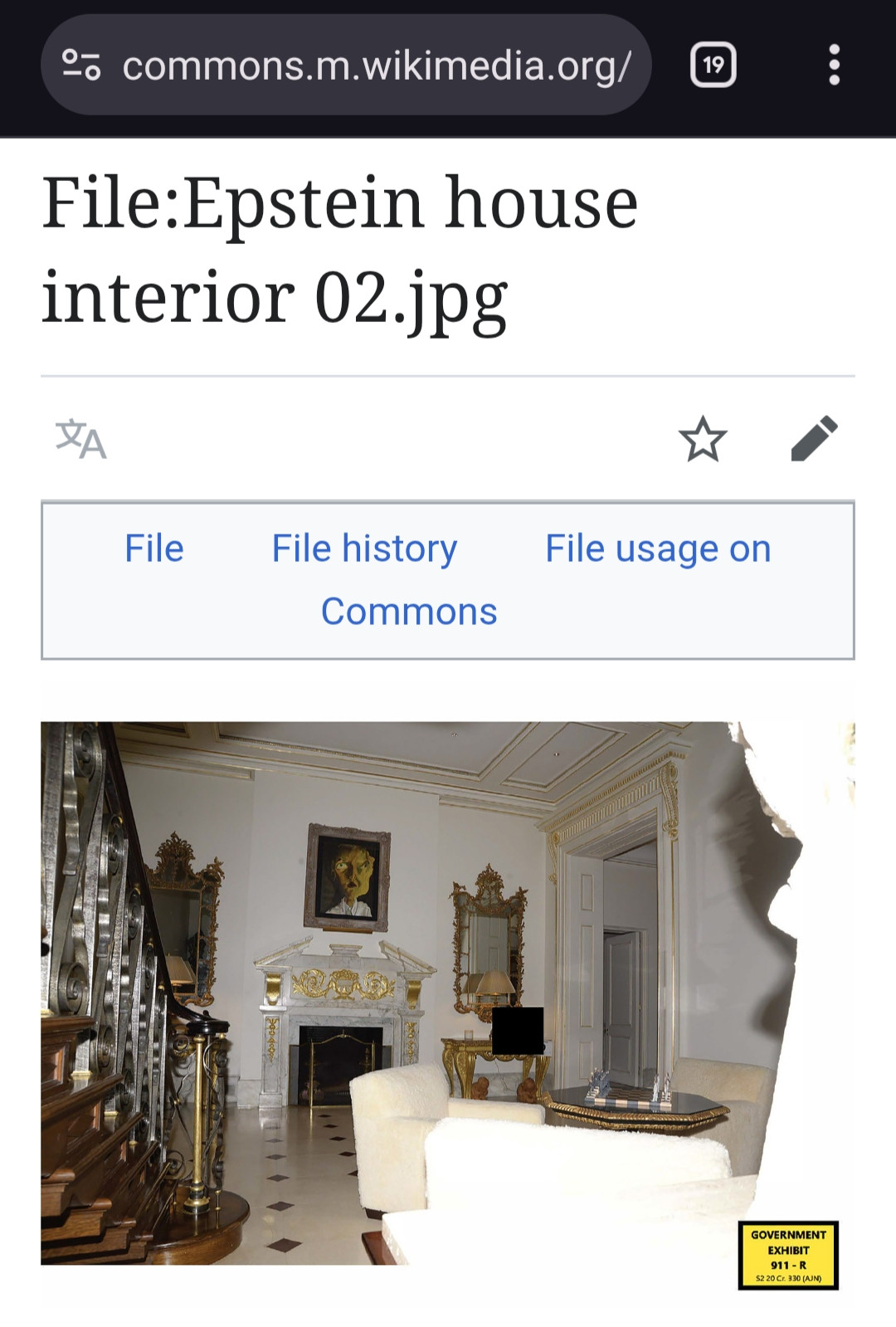 Wikipedia Commons upload of a a photo of a parlour in Jeffrey Epstein's UES New York City home. Police raid images. Manhattan Federal Ghislaine Maxwell trial evidence exhibit.

a white fireplace surround with a lot of gold leaf decorations and ornate golden framed mirrors and pictures 

https://commons.m.wikimedia.org/wiki/File:Epstein_house_interior_02.jpg