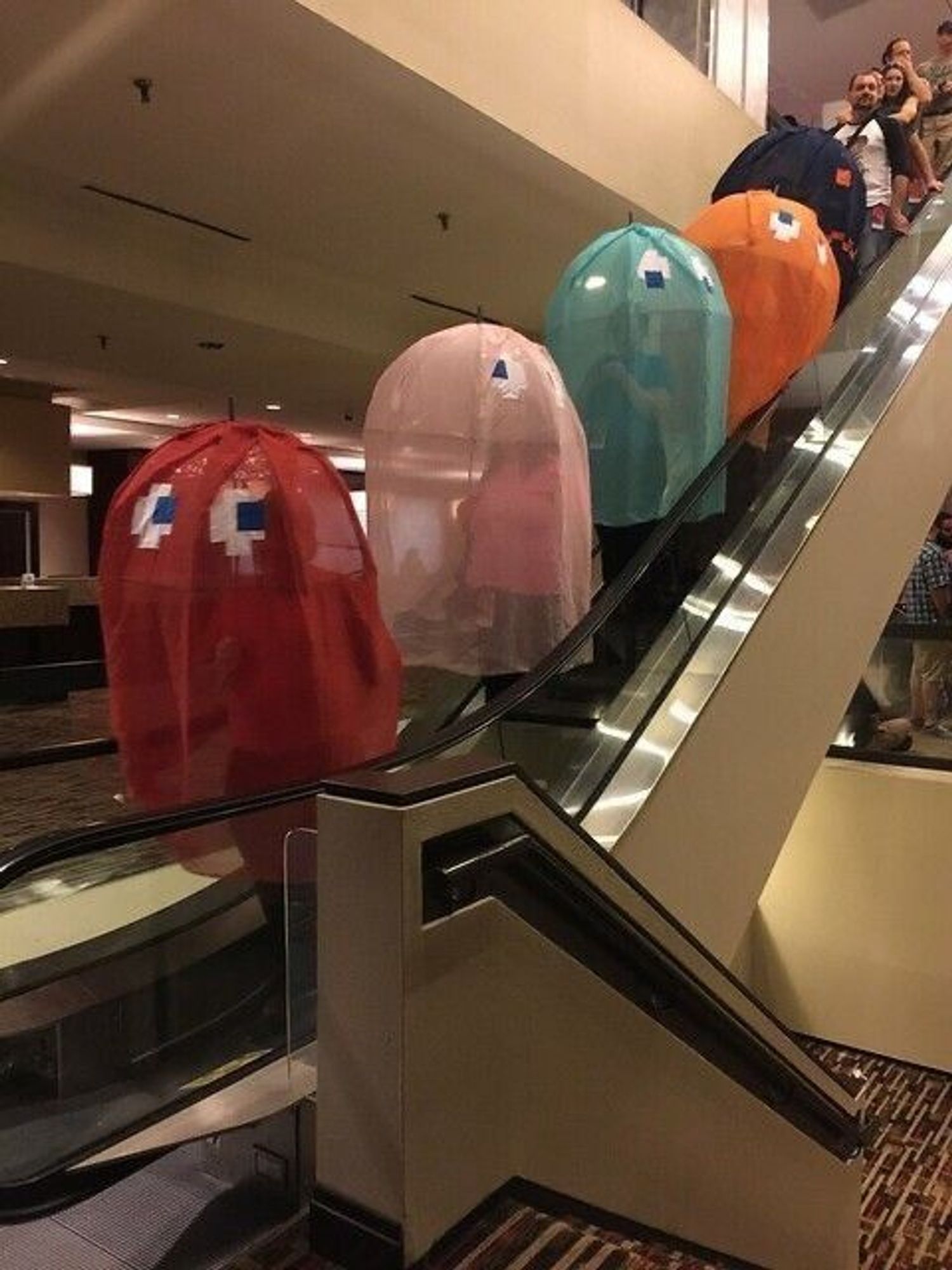 several people wearing pacman ghost costumes on an escalator. the costumes are made of umbrellas and some kind of tulle fabric