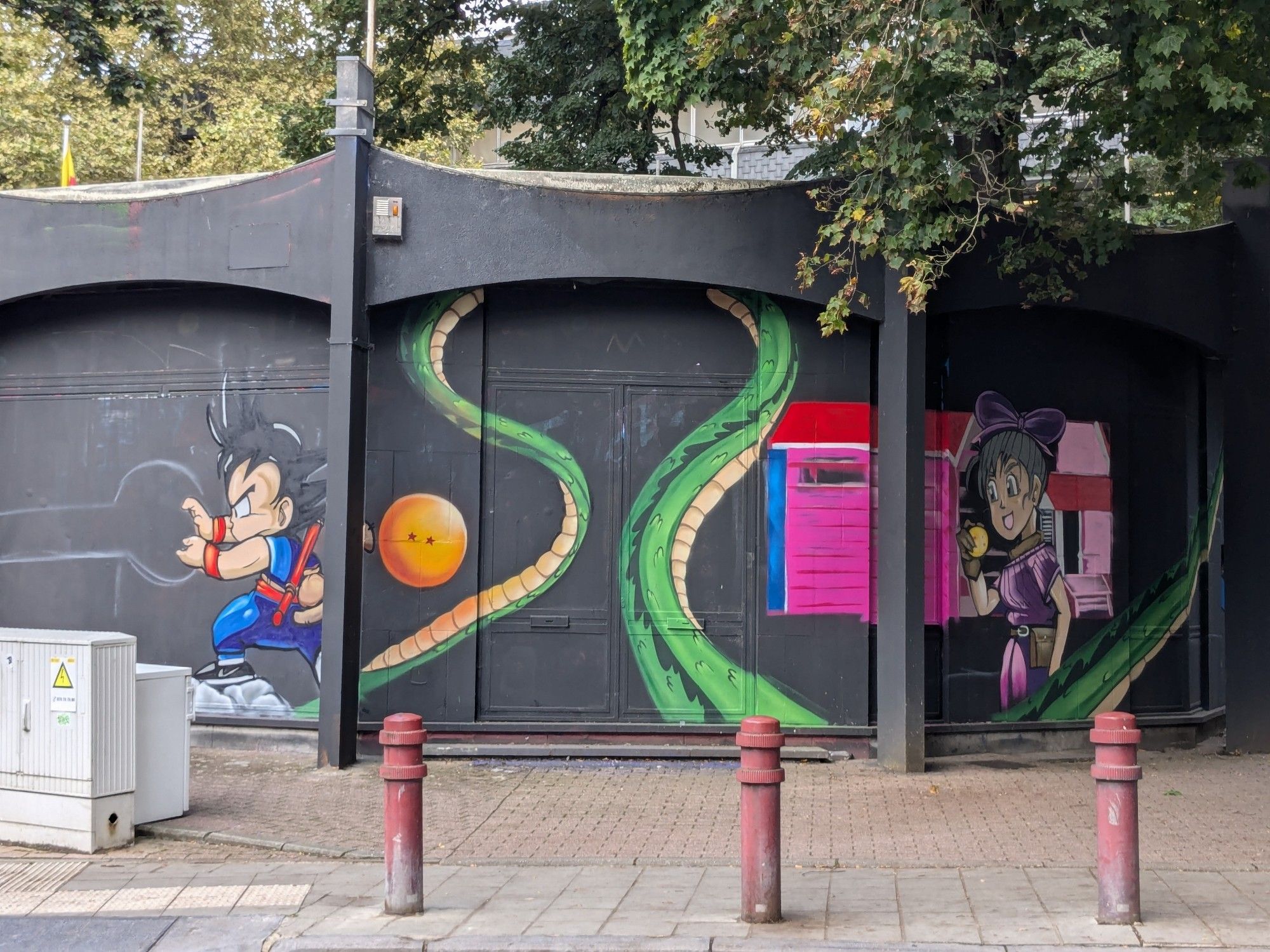 Graffiti on a building showing young Goku throwing a Kamehameha on the left (not yet finished). A two star dragonball and a part of the dragon. On the right side young Bulma with a dragonball in her hand in front of a house