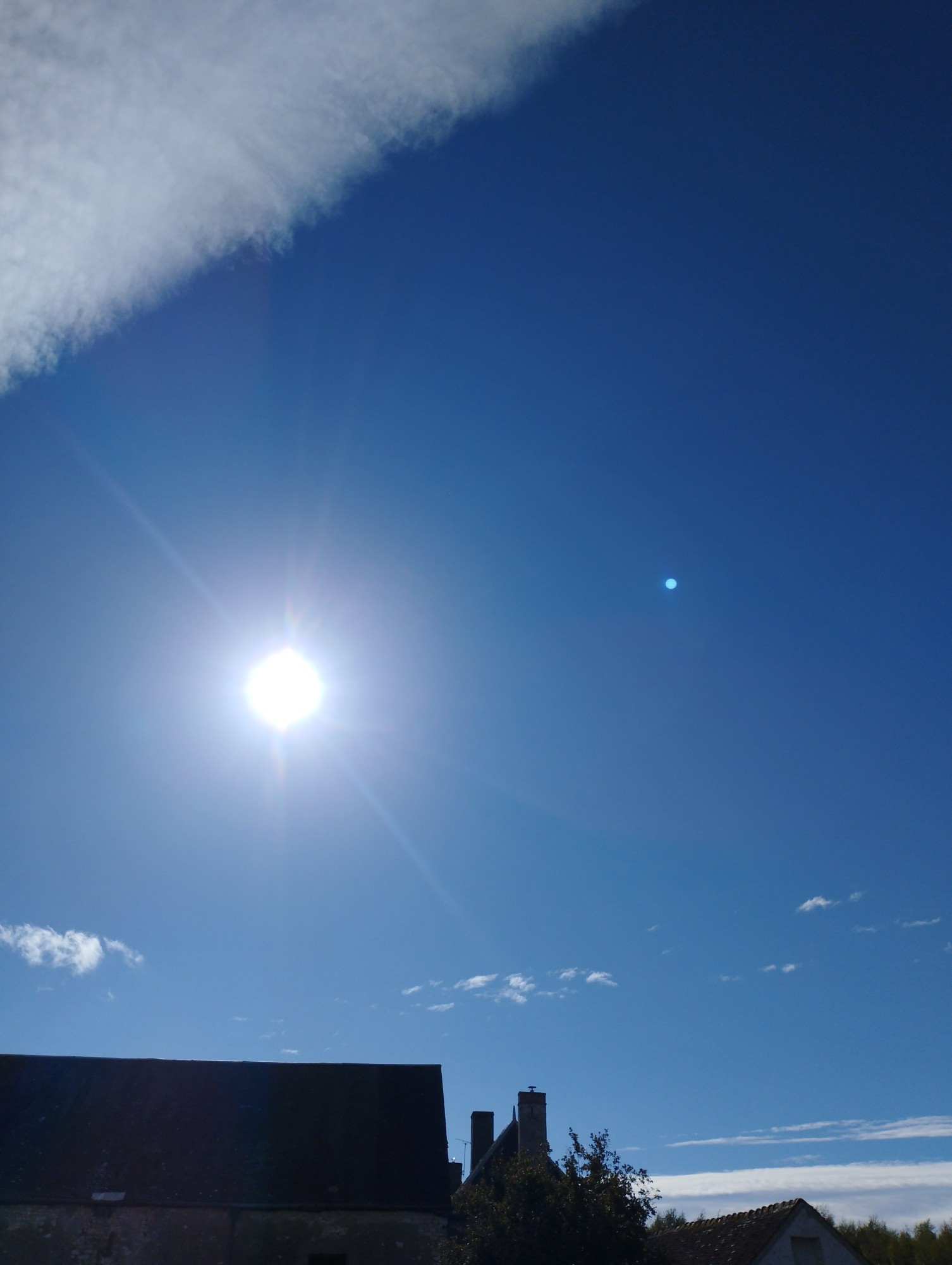 Photo du ciel bleu depuis la terrasse de Louphoque. On voit le soleil blanc et quelques trainées nuageuses