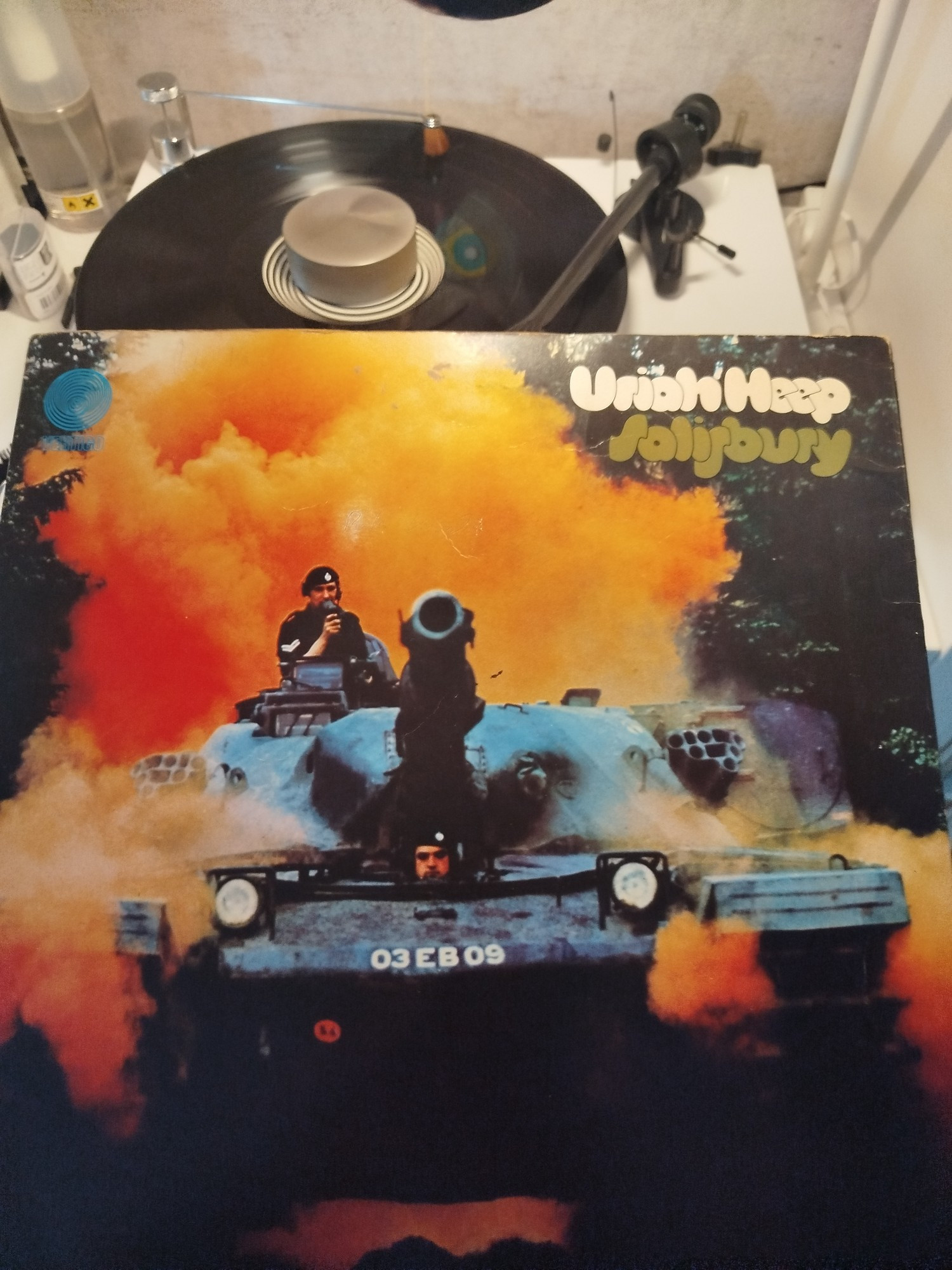 Auf dem Bild ist das Albumcover des Musikalbums „Salisbury“ von Uriah Heep zu sehen. Im Vordergrund steht ein Panzer (genauer ein britischer FV 603 Saracen), der direkt auf die Kamera gerichtet ist, während er orangefarbenen Rauch oder Staub aufwirbelt. Oben auf dem Panzer befindet sich ein Soldat mit einem Helm und einer Kamera. Der Albumtitel „Salisbury“ und der Bandname „Uriah Heep“ sind in weißer und gelblich-grüner Schrift im oberen rechten Bereich platziert. Im Hintergrund ist ein orangefarbener Nebel oder Rauch, der dem Bild eine dramatische Atmosphäre verleiht. Der Panzer trägt die Kennzeichnung „03EB09“.

Im Hintergrund ist außerdem ein Schallplattenspieler mit einer Schallplatte zu sehen, die gerade abgespielt wird.

