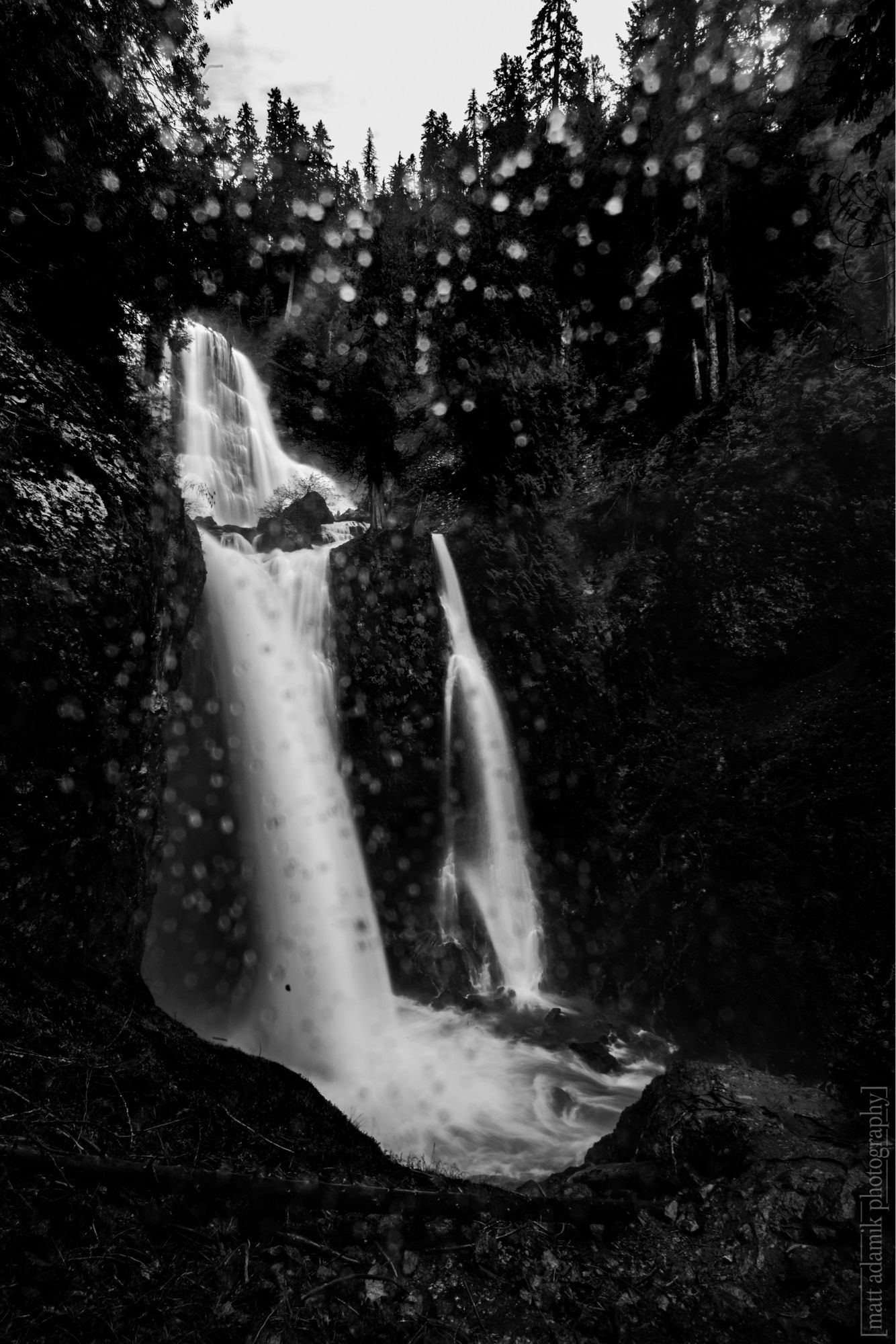 Black and white long exposure of Falls Creek Falls in Washington state with water drops on the camera lens.