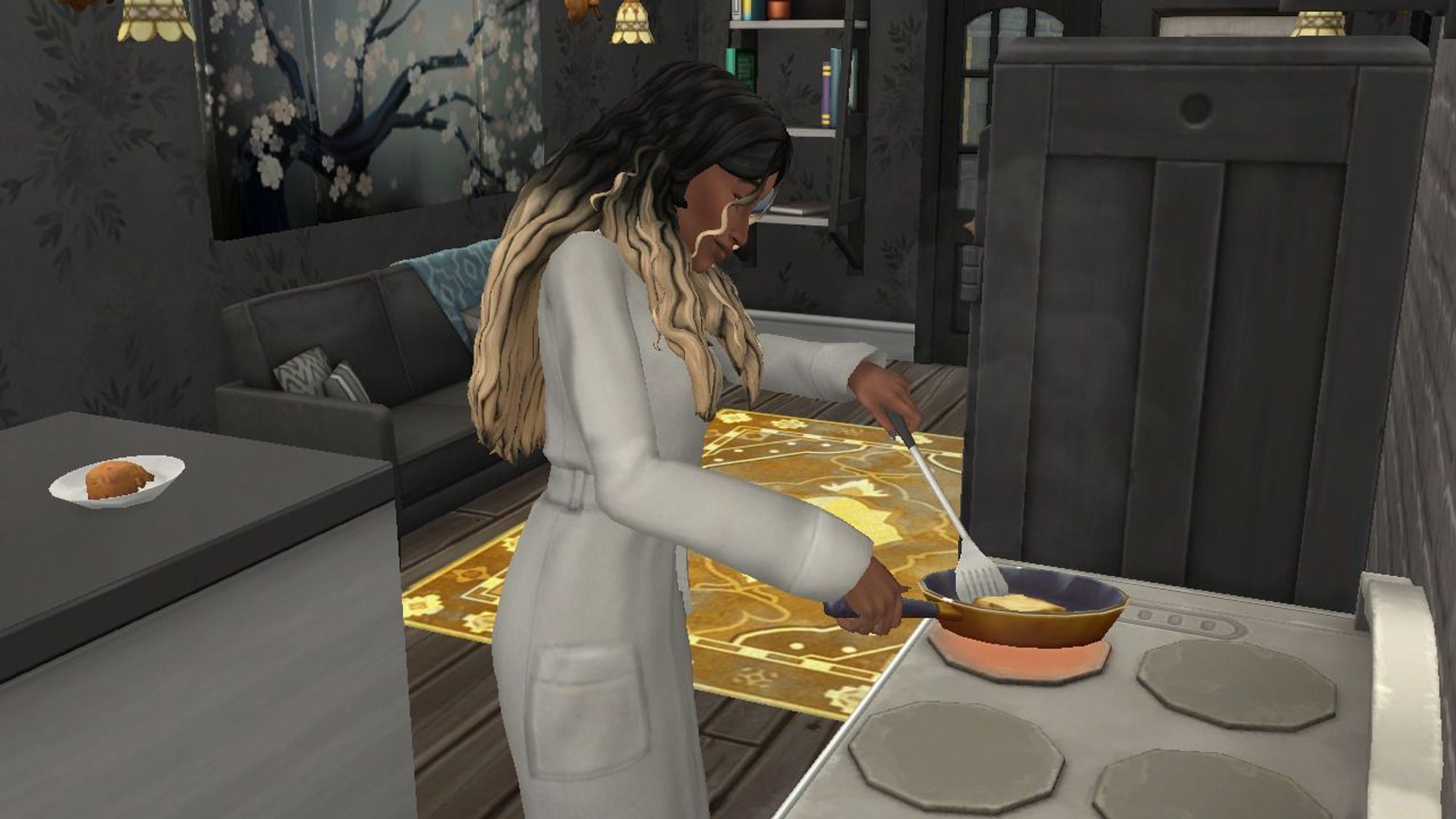 Luna cooks toast & scrambled eggs on the stove in her kitchen while wearing a gray robe.