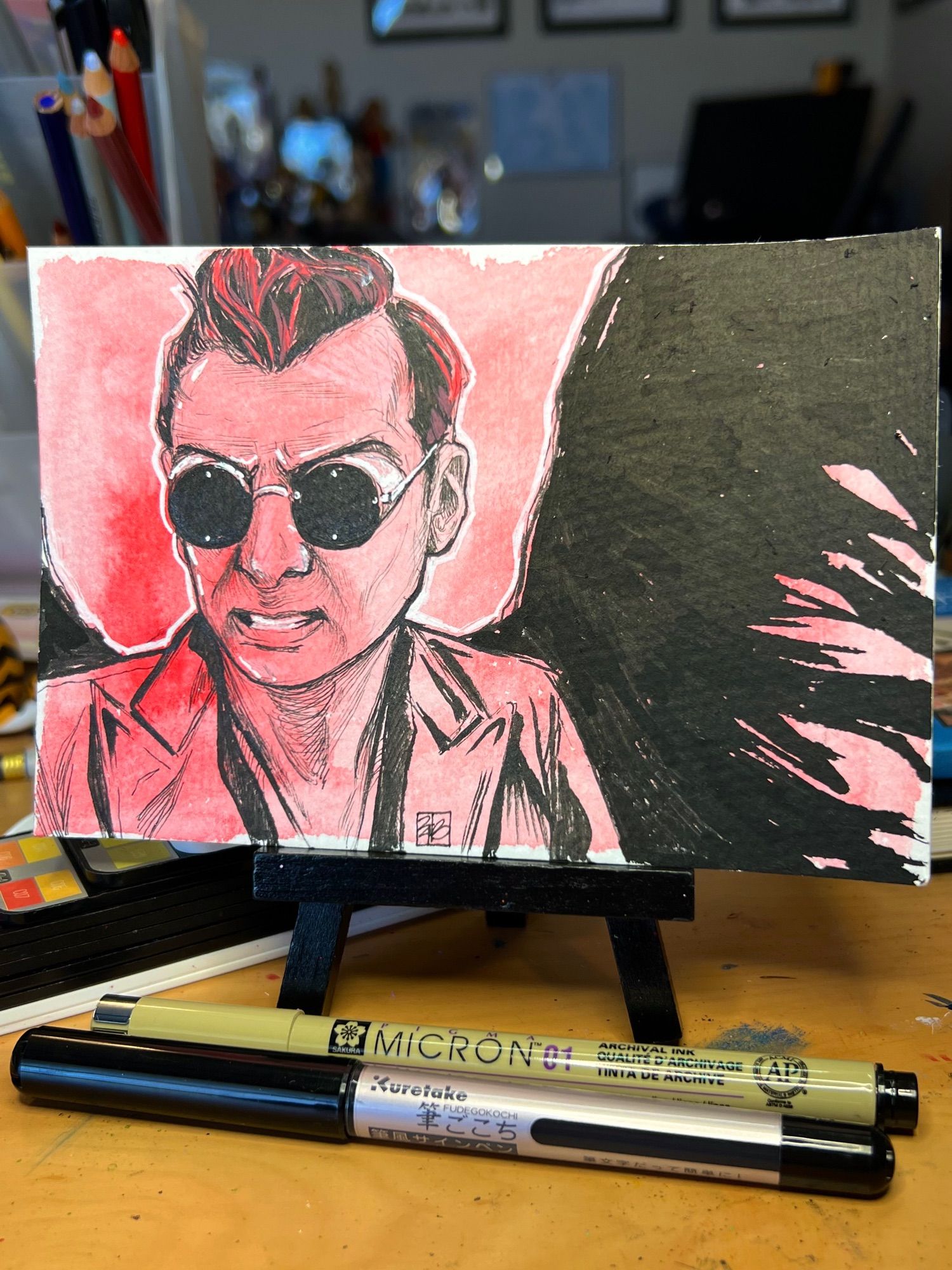 Read watercolor background with an all ink sketch of Crowley from Good Omens wearing his sunglasses