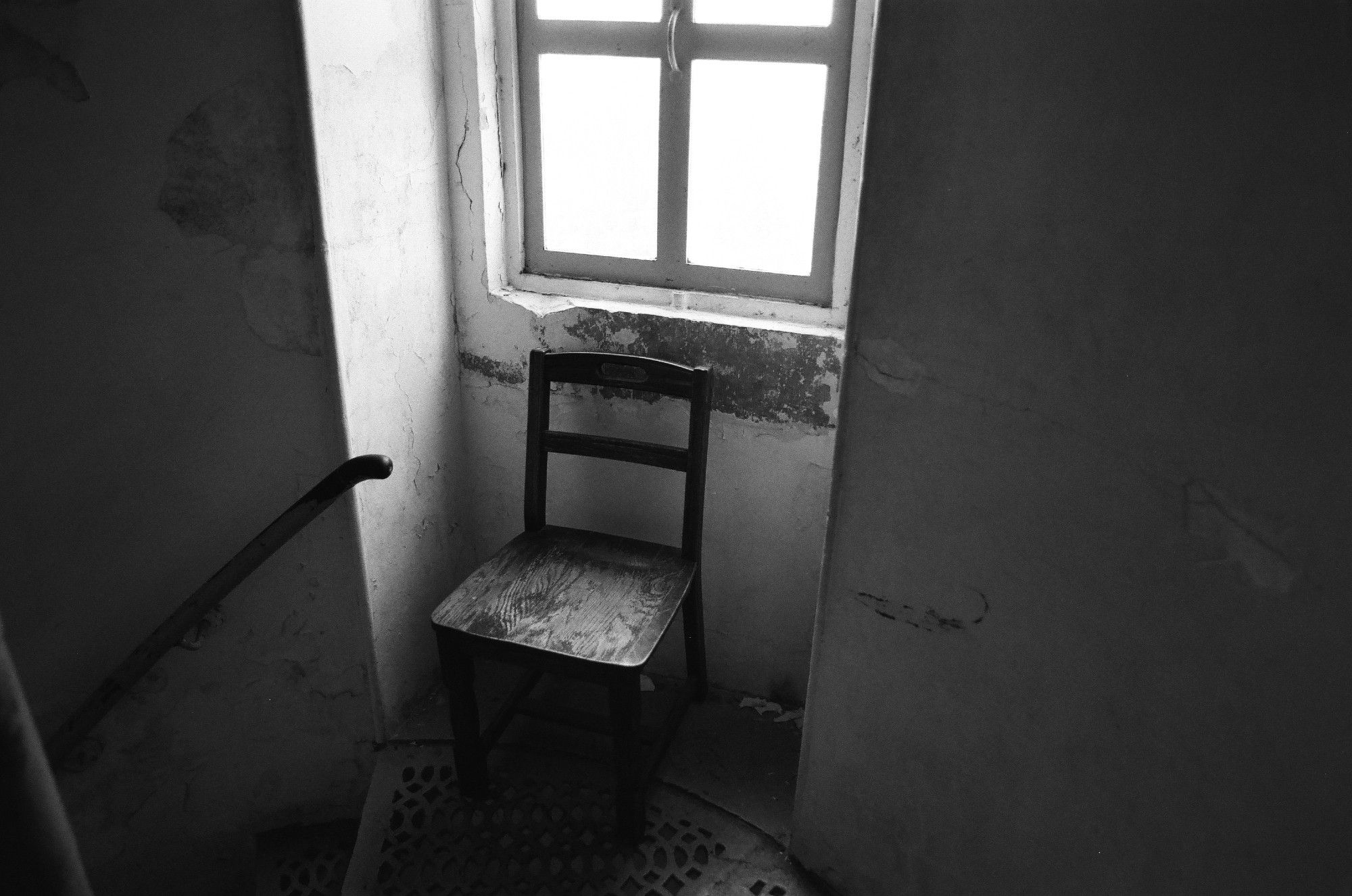 A photo of a chair underneath a window inside of a lighthouse tower.