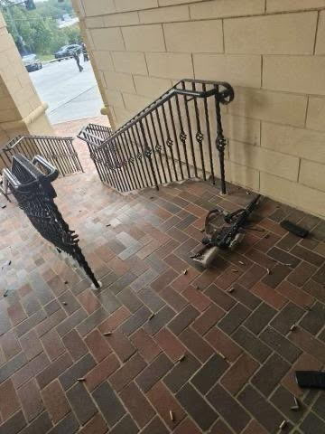One rifle and many shell casings on the ground near an outdoor staircase 