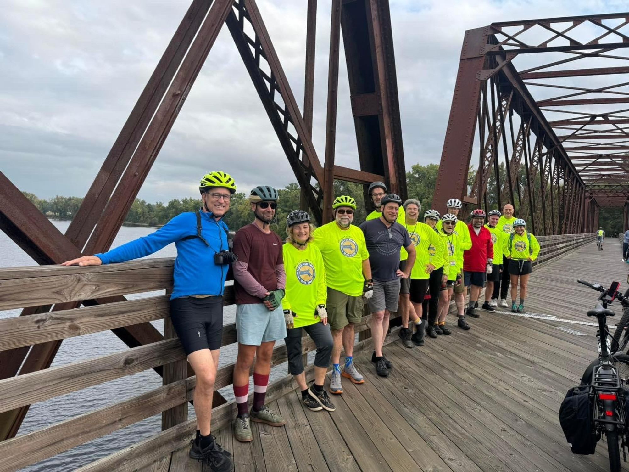 A group of people wearing bicycle helmets pose on the old truss railroad bridge across the Connecticut River as an awareness building campaign to complete construction of the Massachusetts Central Rail Trail connecting 104 miles from Northampton to Boston