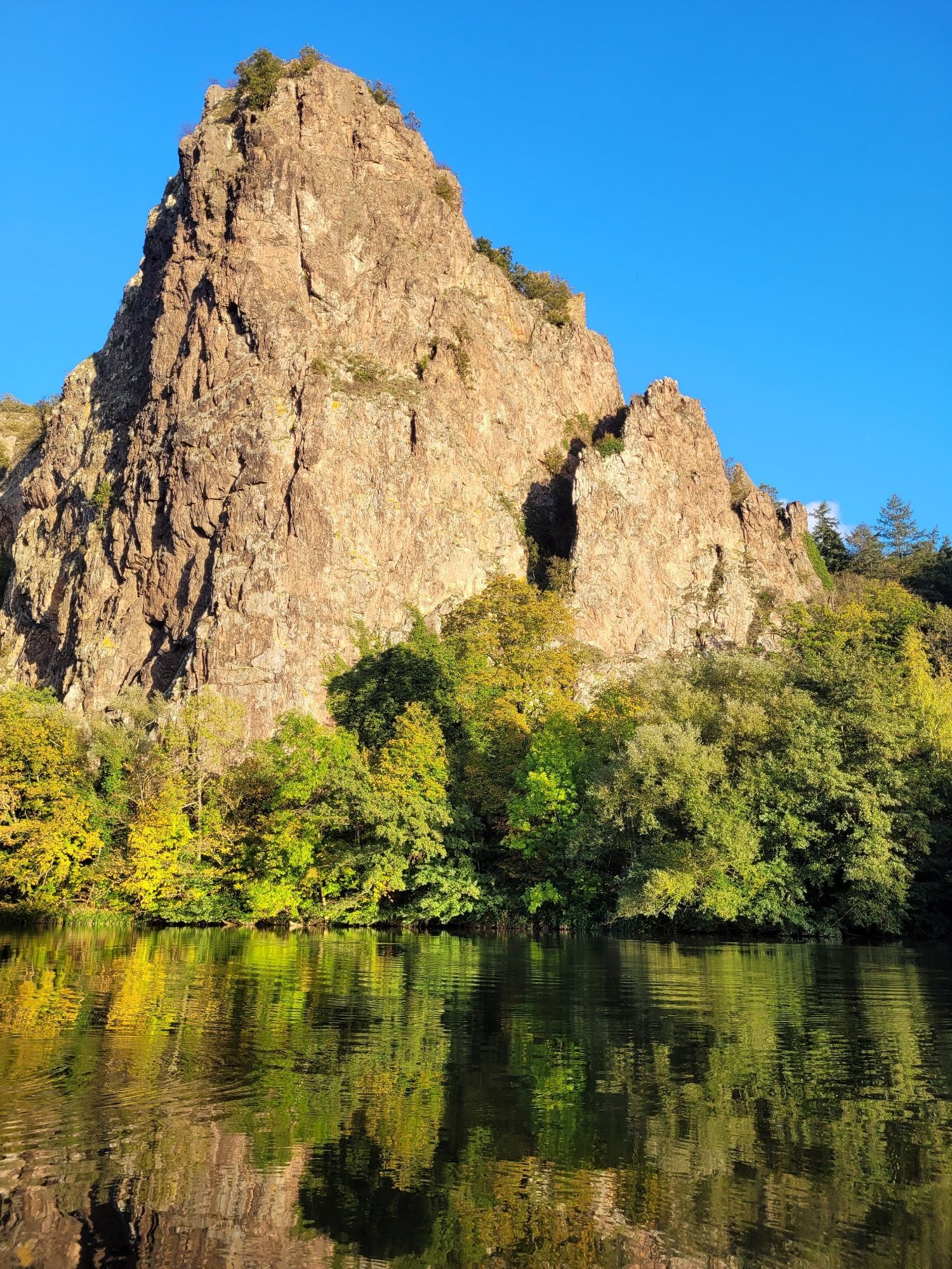 Rheingrafenstein vom Ufer der Nahe inklusive Nahe im unteren Bereich mit tiefblauem Himmel über dem Fels