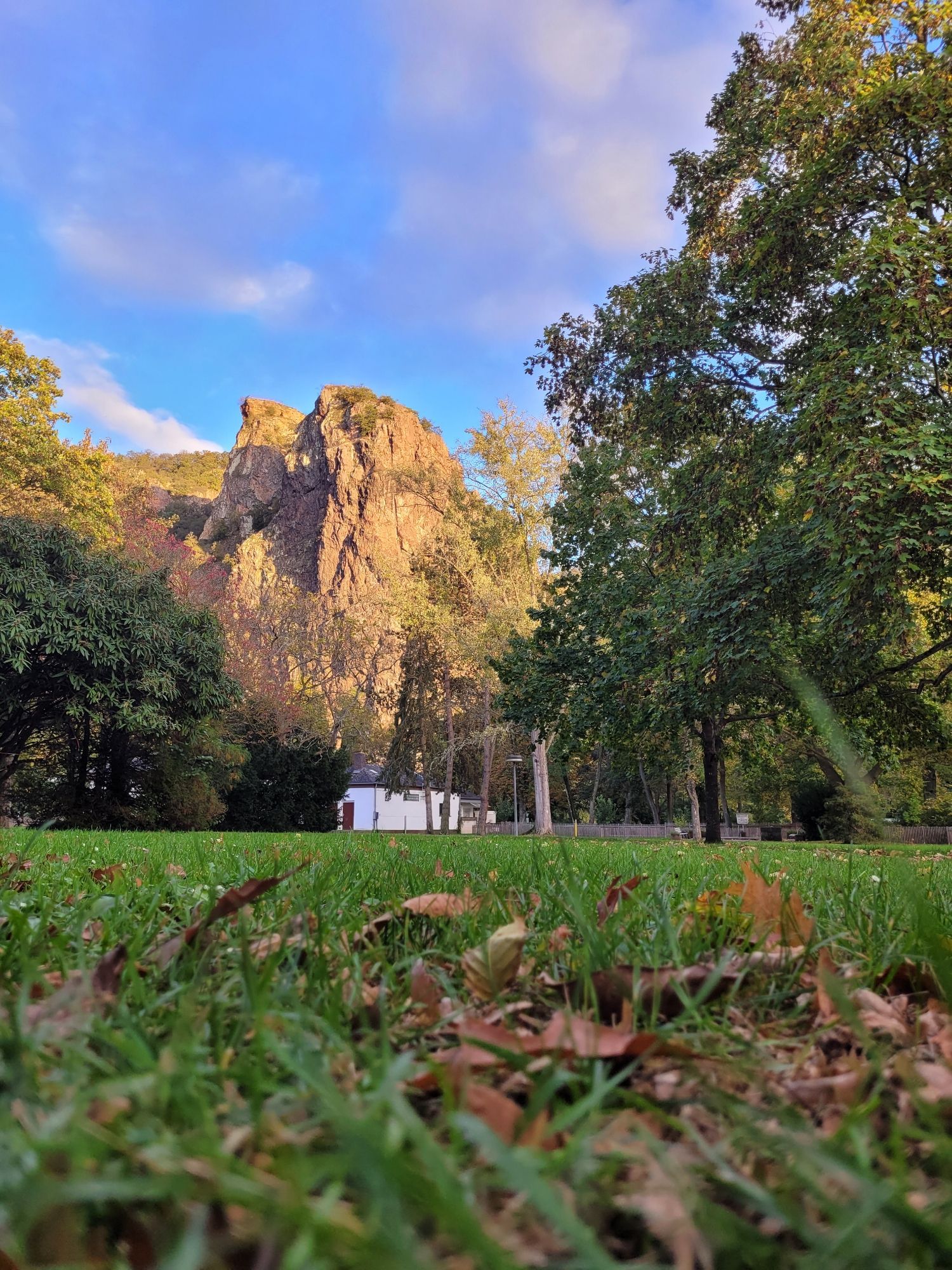 Bild vom Rheingrafenstein vom Kurpark Bad Münster am Stein-Ebernburg aus gesehen mit blauem Himmel und Wolken