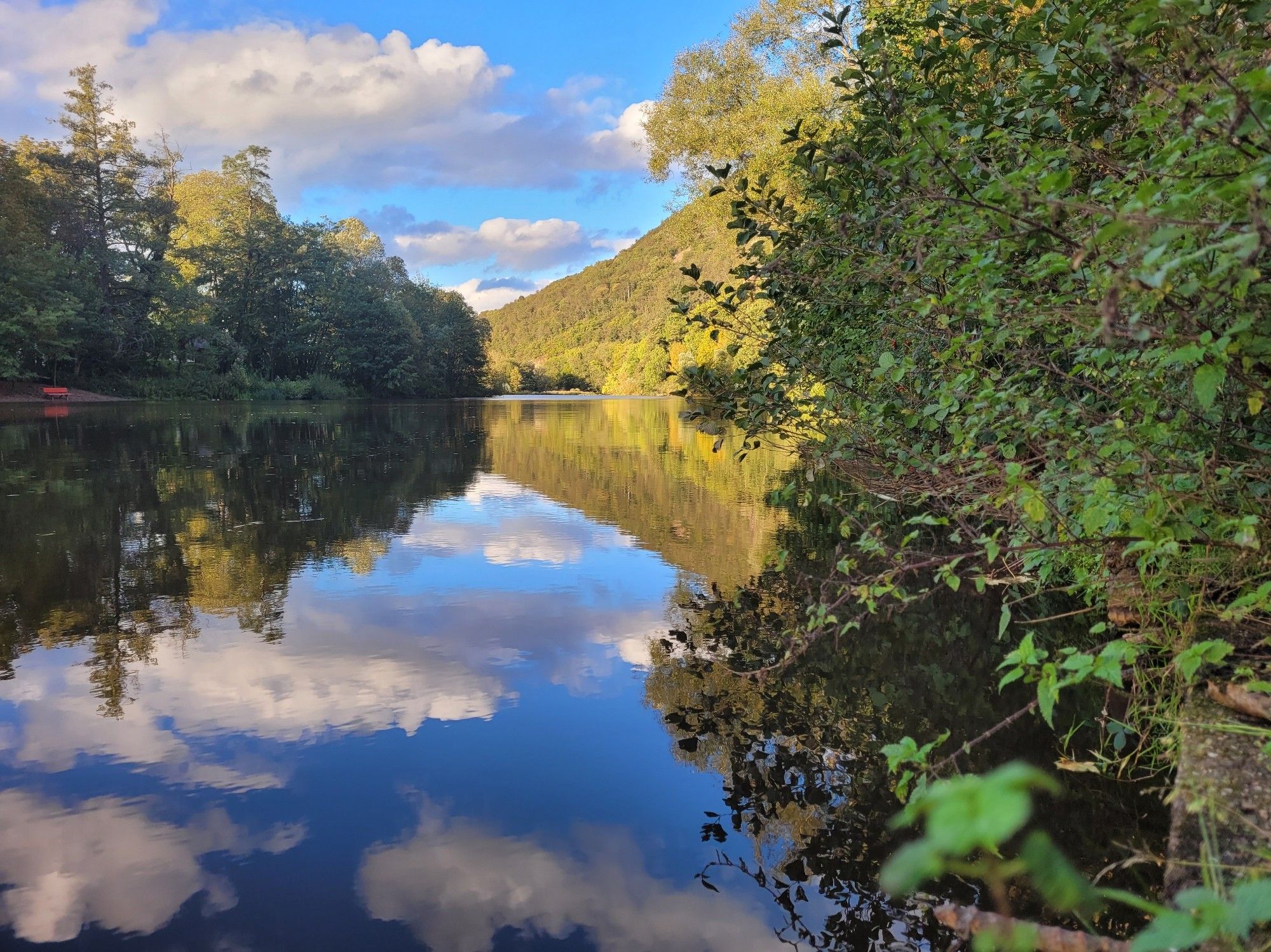 Fluß Nahe vom Ufer am Fuß des Rheingrafensteins an der Fähranlegestelle mit tollen Wolken auf blauem Himmel und Reflexionen