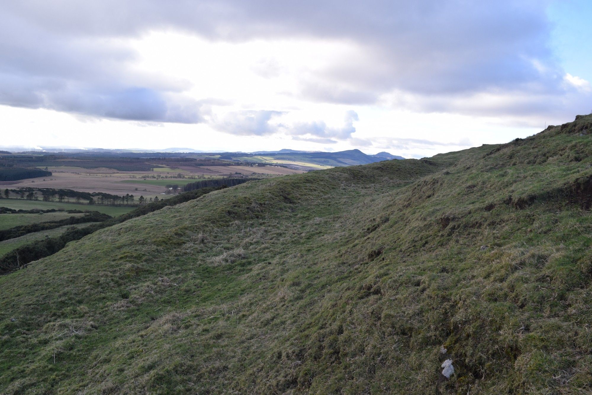 The outer rampart and ditch with the Lomond hills in the background.