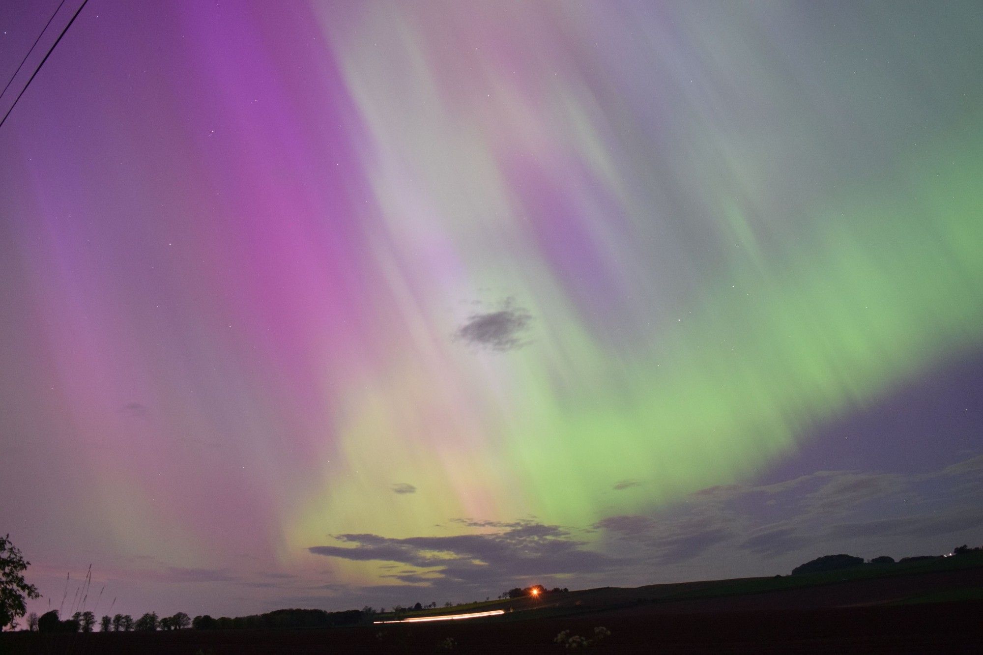 Purple and green aurora fill the sky above the silhouette of the horizon.