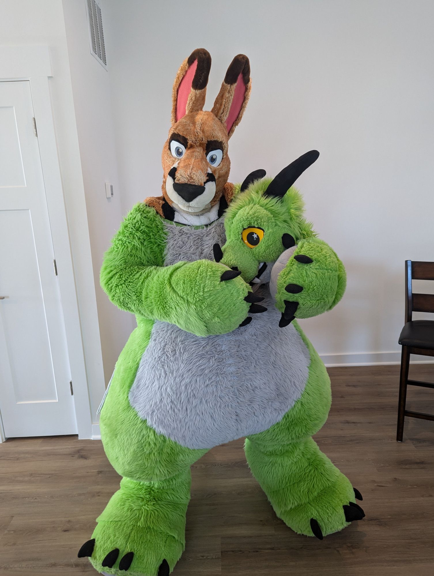 picture of a Kangaroo fursuiter with Paradise the plush dragon as a second fursuit layer, while holding Paradise's head in their hands