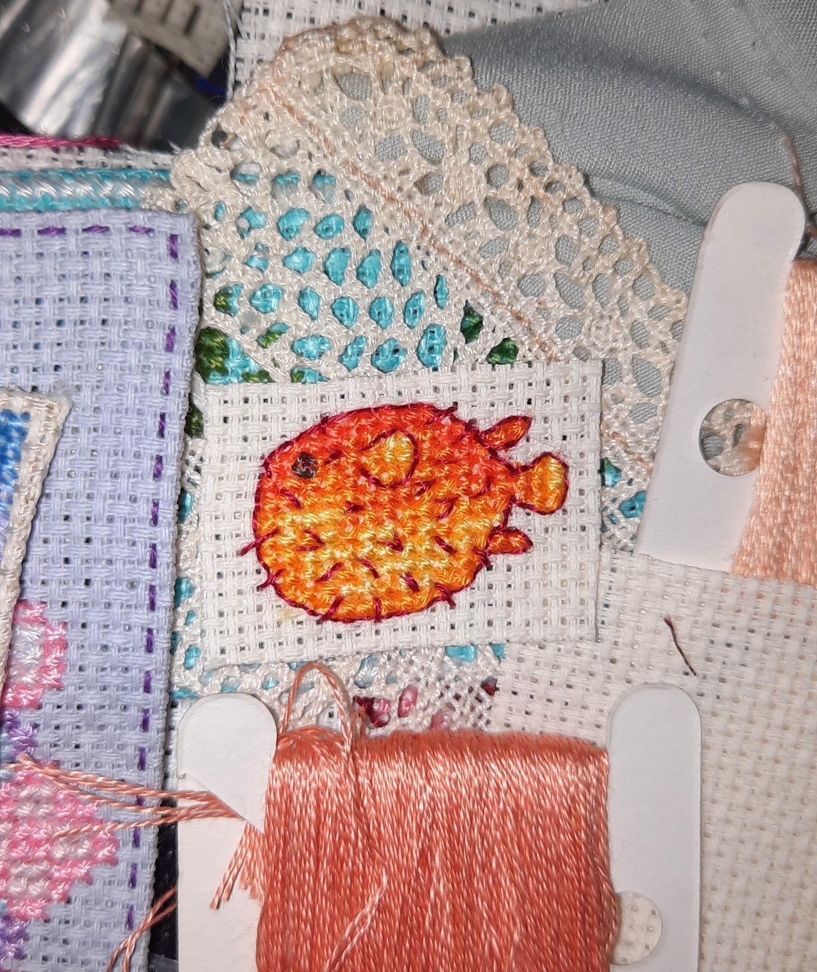 A tiny cross stitched fugu in vivid orange shades.