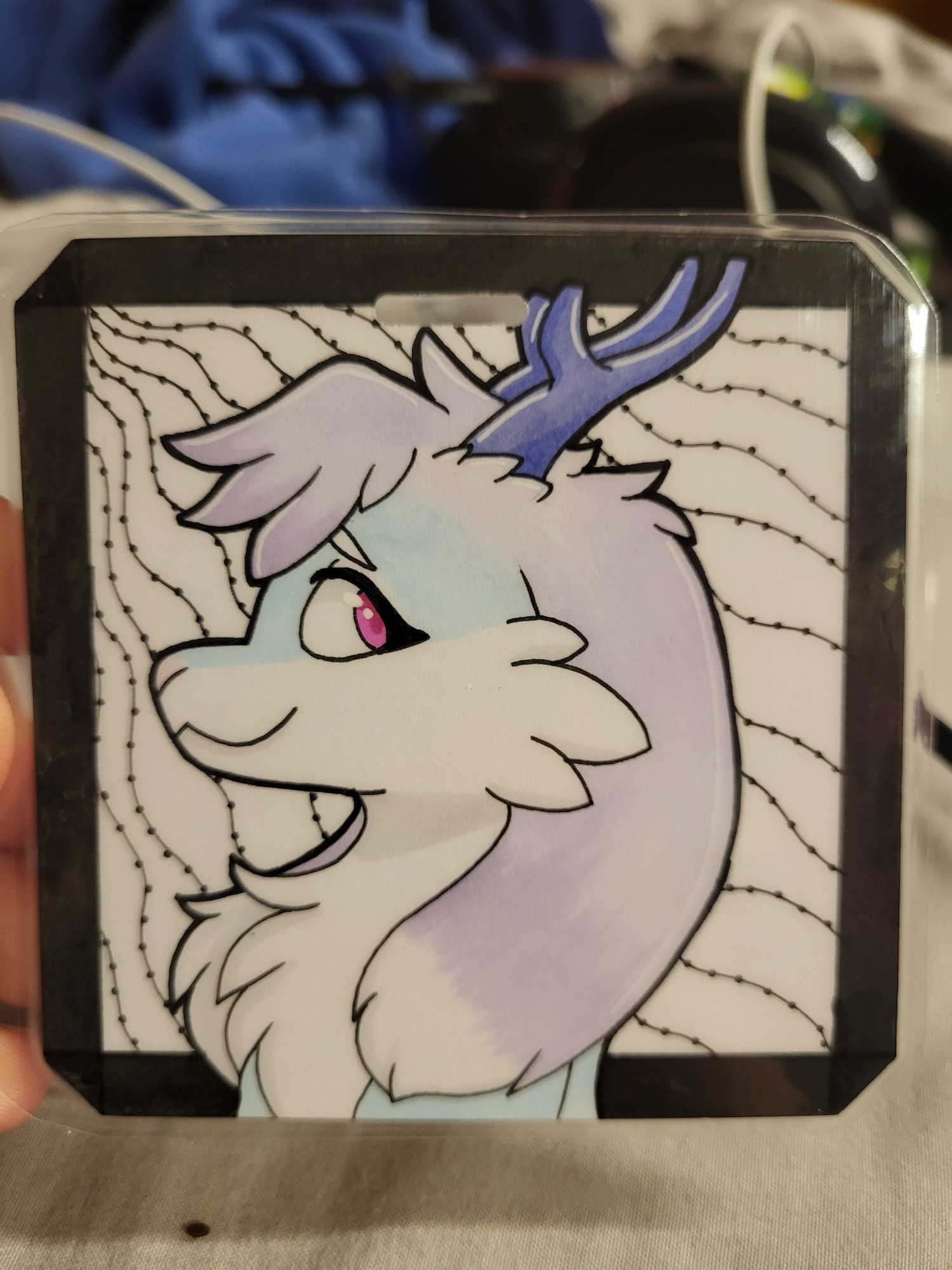 Headshot of a jackalope (Vail) facing the left with white, baby blue and pastel purple fur, purplish blue horns, and pink eyes.