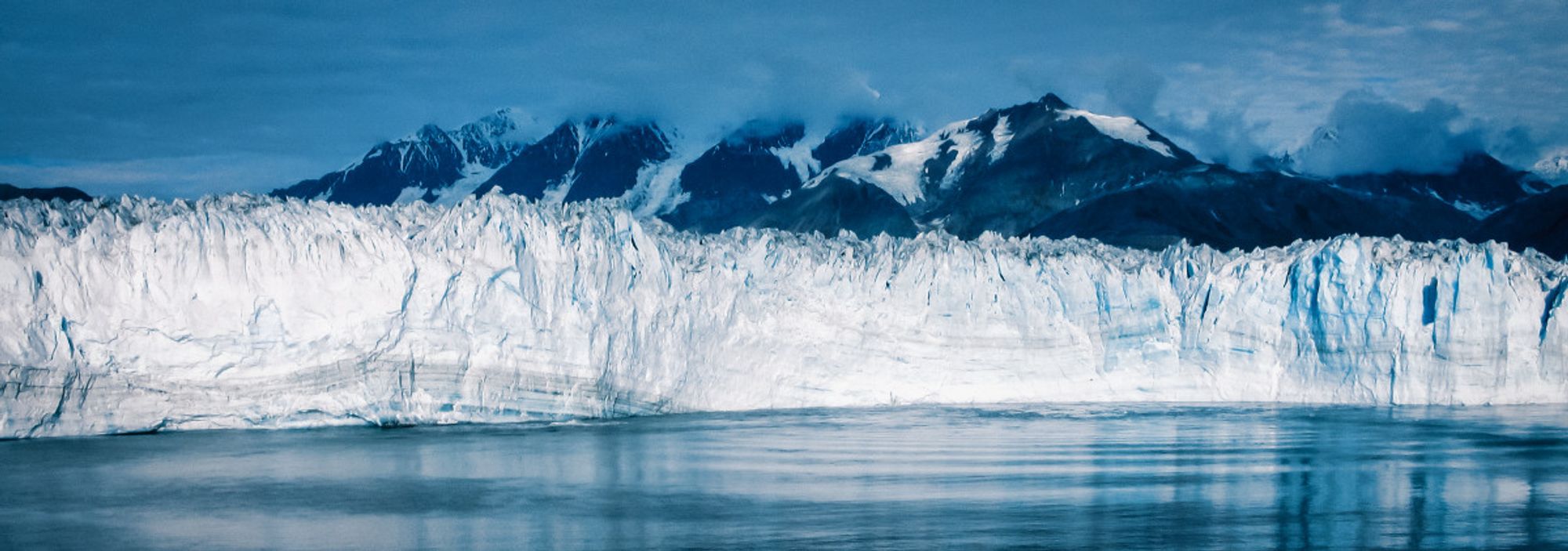 Icy ocean currents swirl around the base of where an Alaska glacier meets the sea.