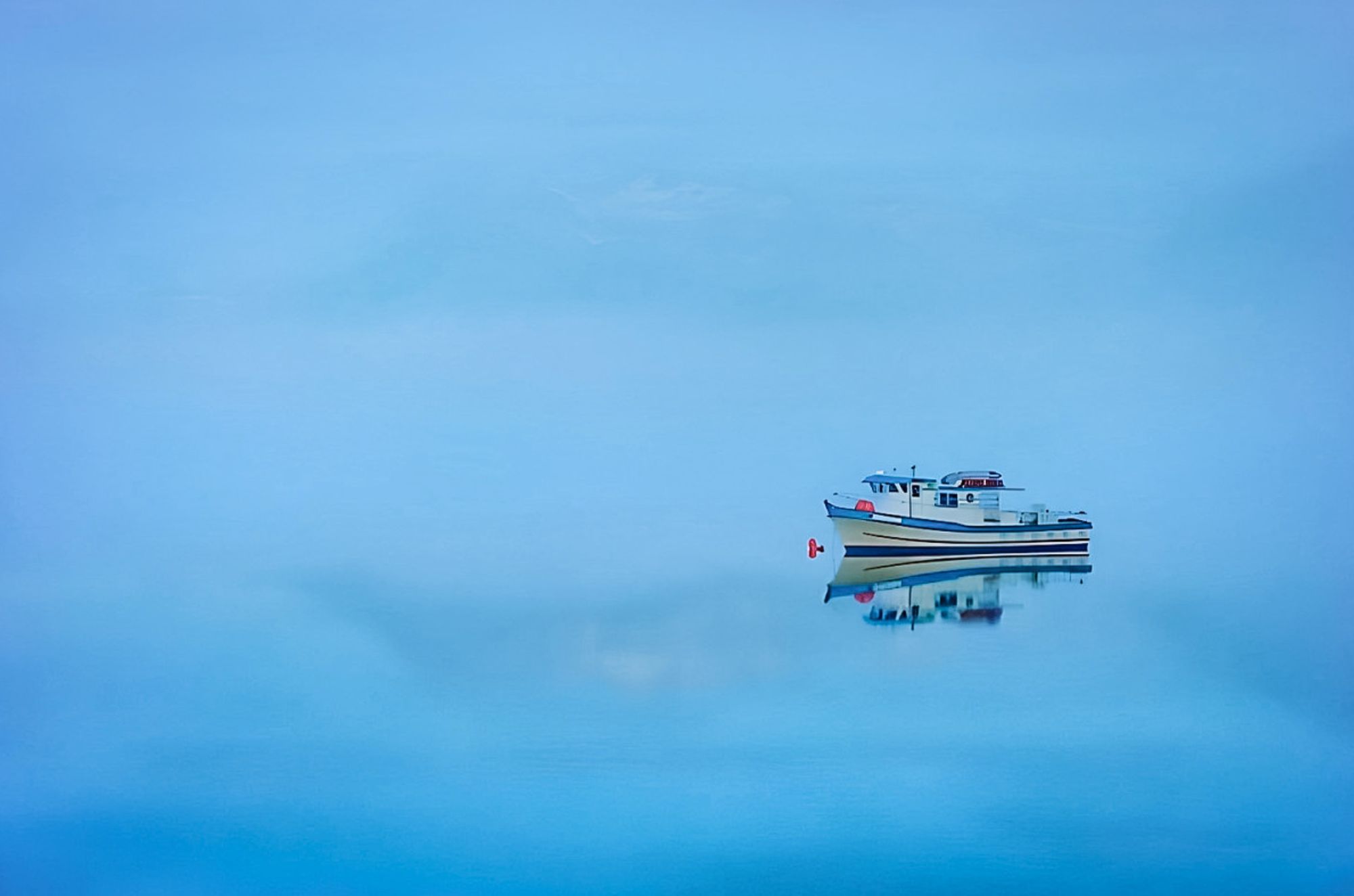 An Alaskan fishing boat floats into mist on still water