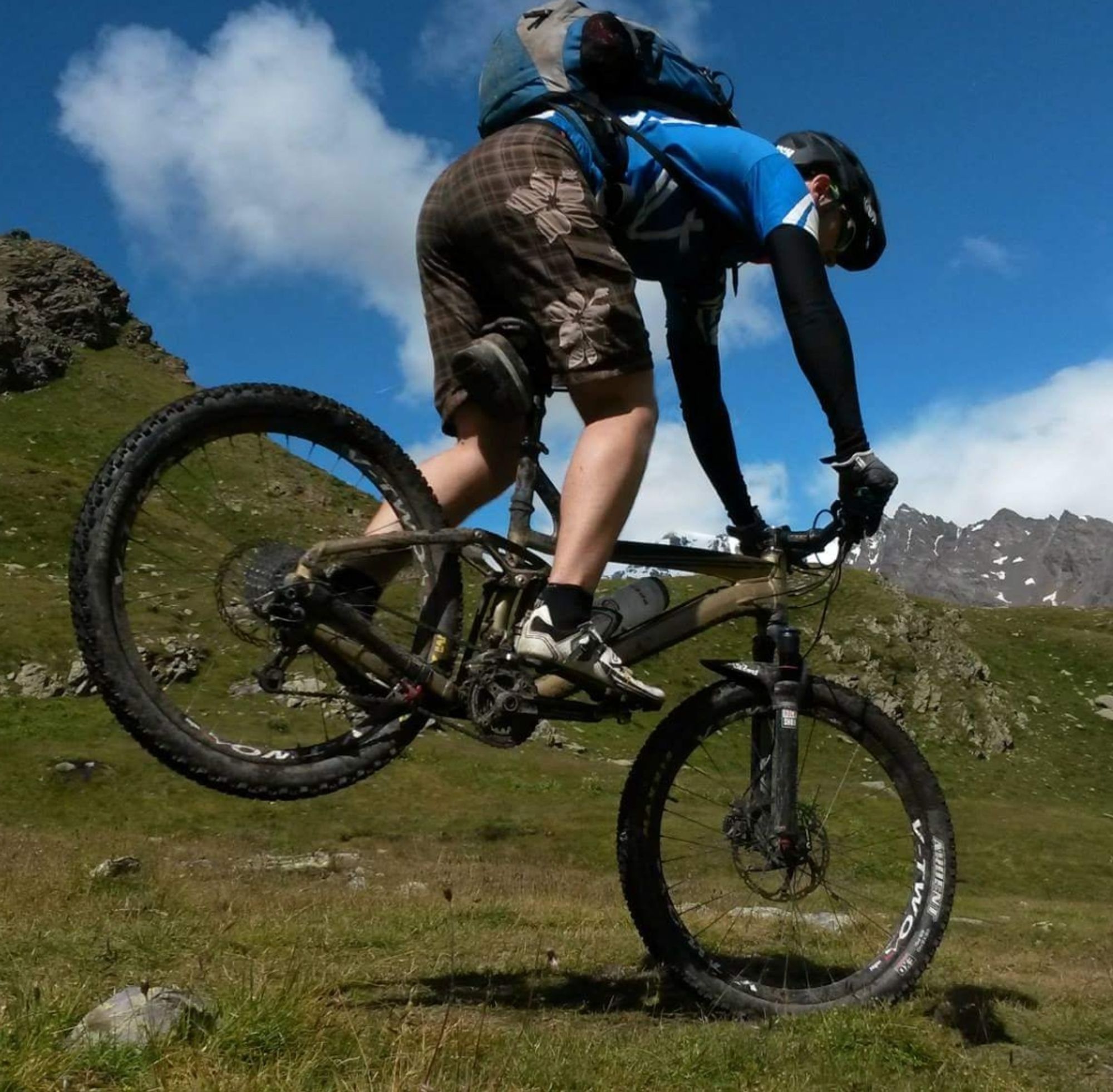 Stoppie in hochalpinen Gelände mit einem gold-schwarzem MTB