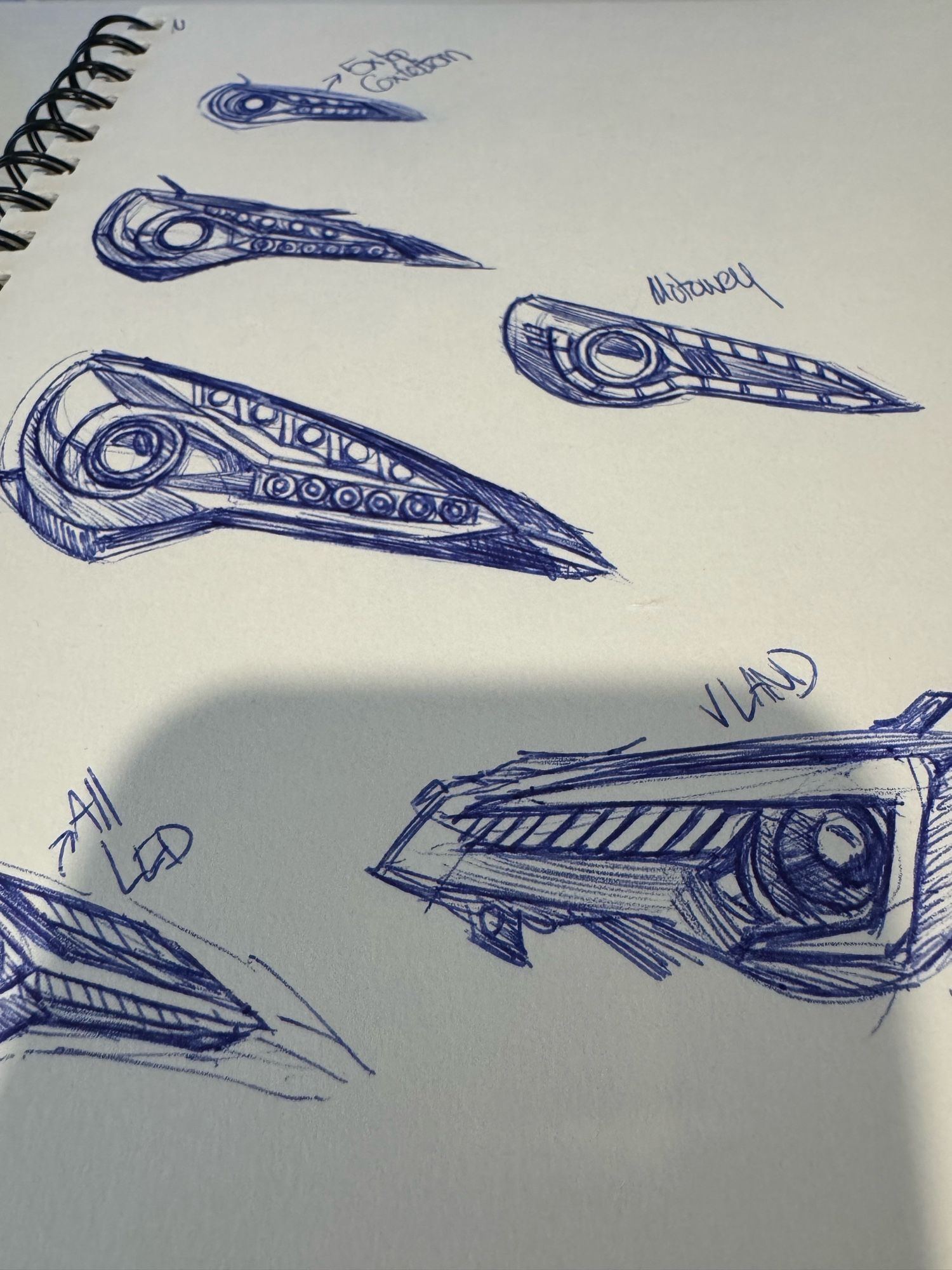 Ink drawing in a sketchbook of different headlight designs.