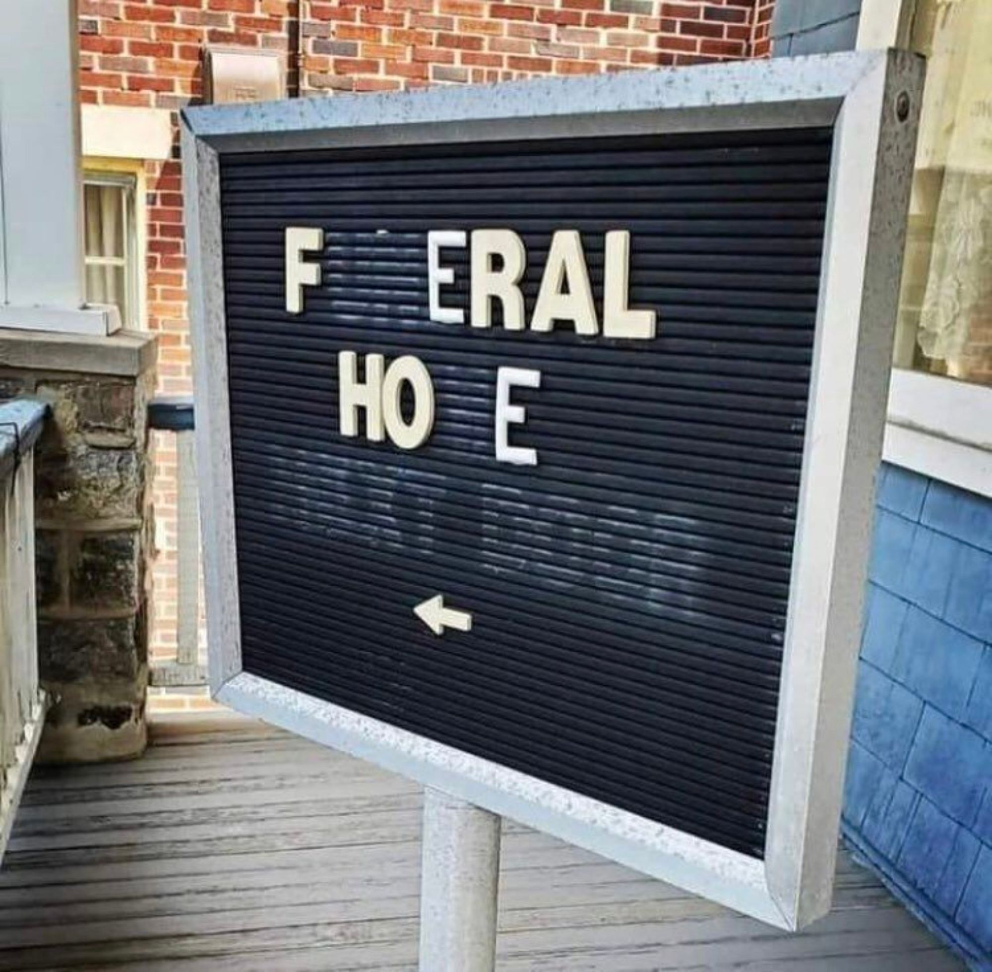 a sign for a funeral home where letters have fallen out, leaving only the words FERAL HOE