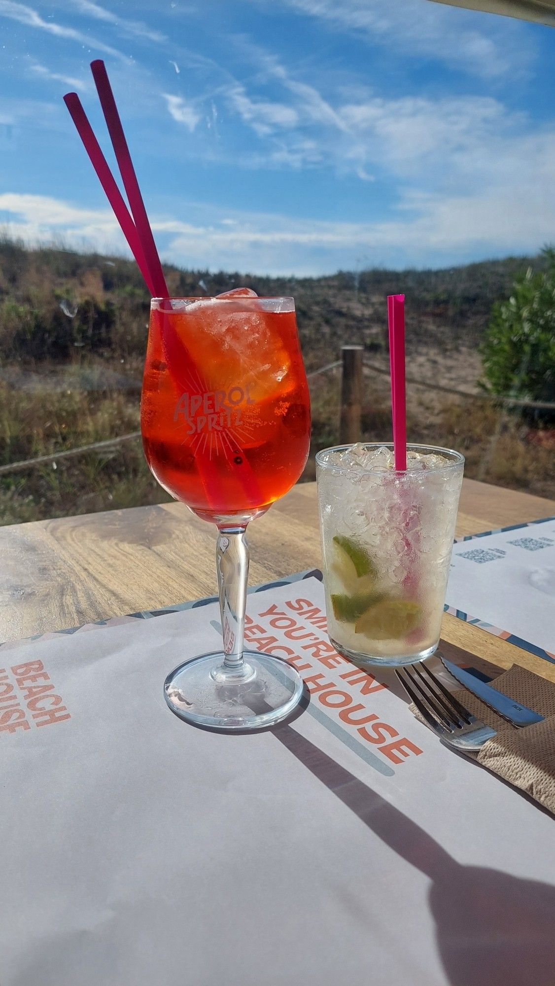 Aperol Spritz und Caipirinha vor strahlend blauem Himmel vor Strand