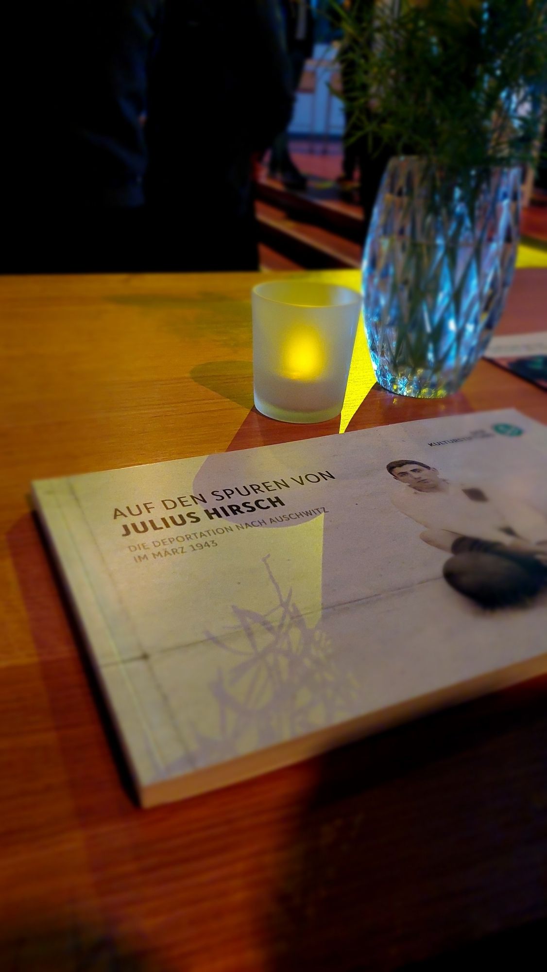 Buch "Auf den Spuren von Julius Hirsch" auf einem Tisch mit Kerze und Vase