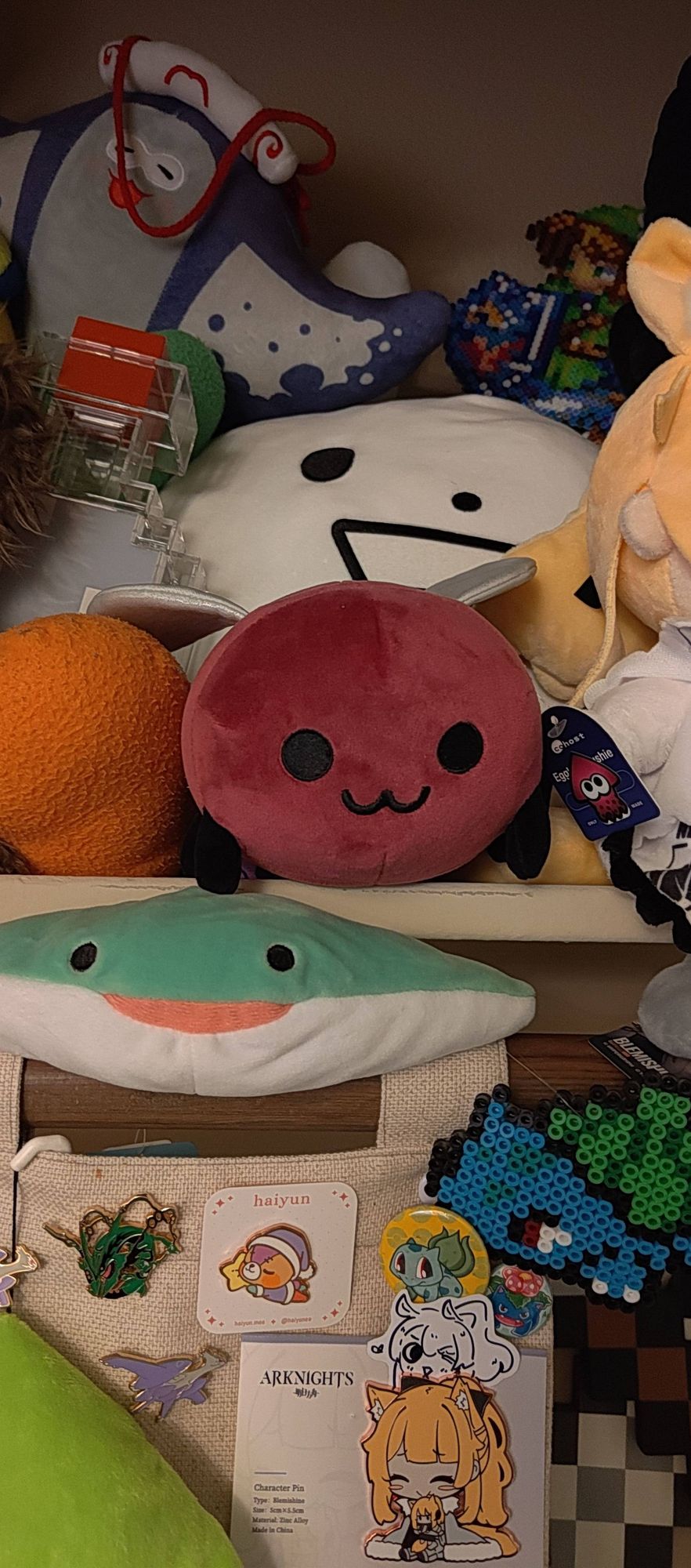 My Eggbug plushie on the plushie shelf. There is a small Splatoon sticker to differentiate it from others