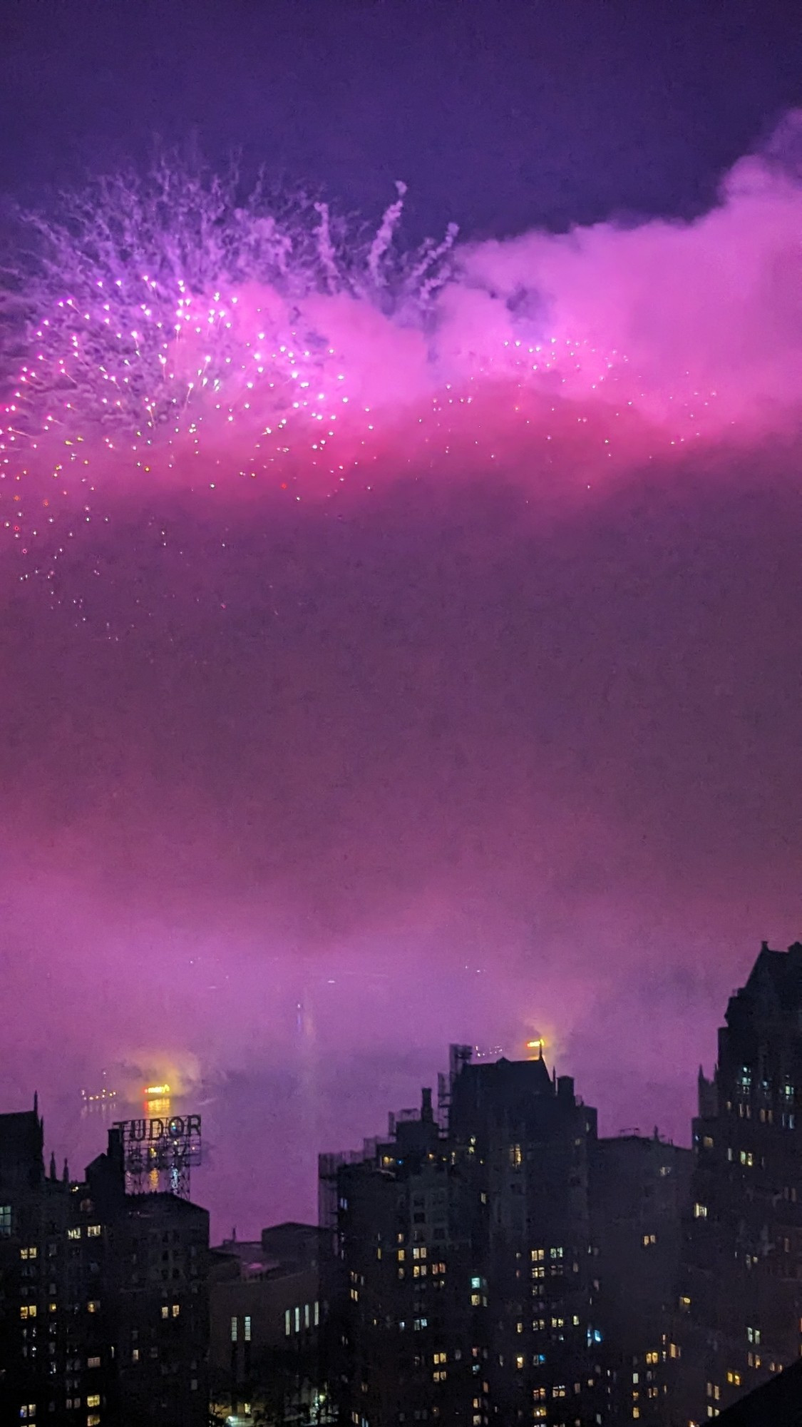 Pink Fireworks over the East river illuminating a plume of smoke that gathered due to the amount of fireworks that burst.  