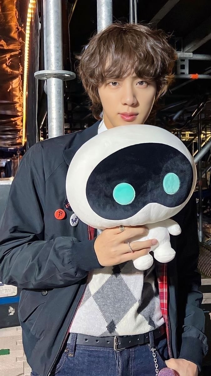 Jin of BTS with Wotteo, the plushie he created as merch for the release of his song The Astronaut