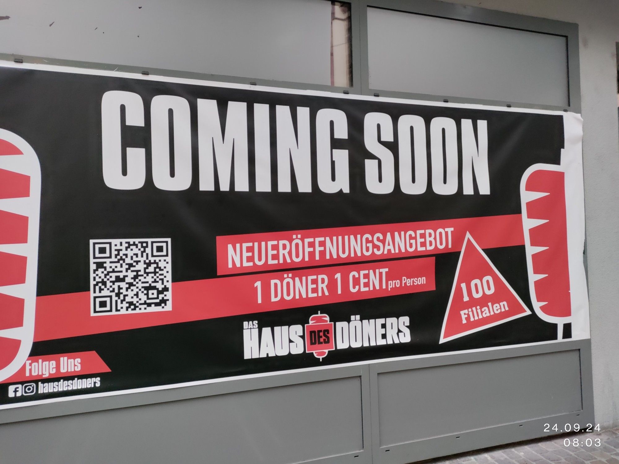 Plakat im Schaufenster, das die Neueröffnung eines Dönerladens ankündigt. Eröffnungsangebot ein Döner 1 Cent (pro Person)