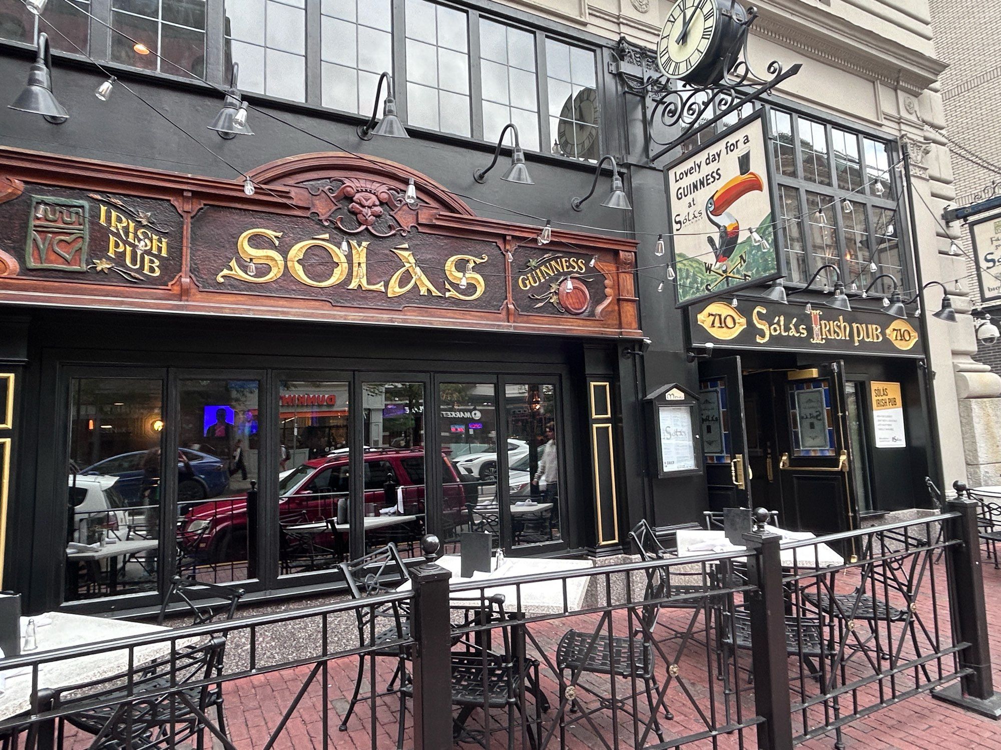 Photo of the front of an Irish pub in Boston named “Solas” which includes advertisements for Guinness beer, including one of a toucan balancing a pint of Guinness on its beak with the text “Lovely day for a GUINNESS at Solas”