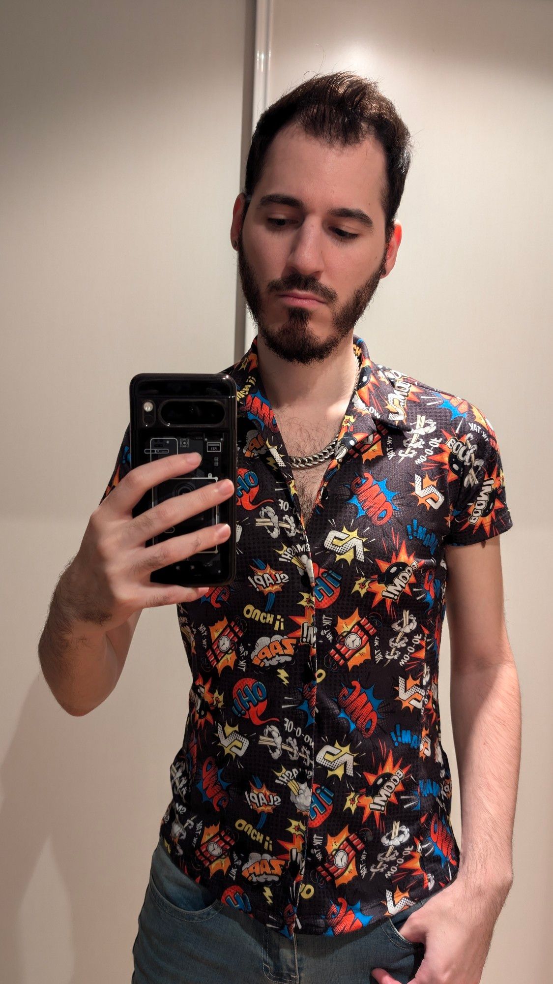 Selfie of a dark haired and beardy man wearing a short sleeve black shirt with comic explosion patterns and blue jeans.