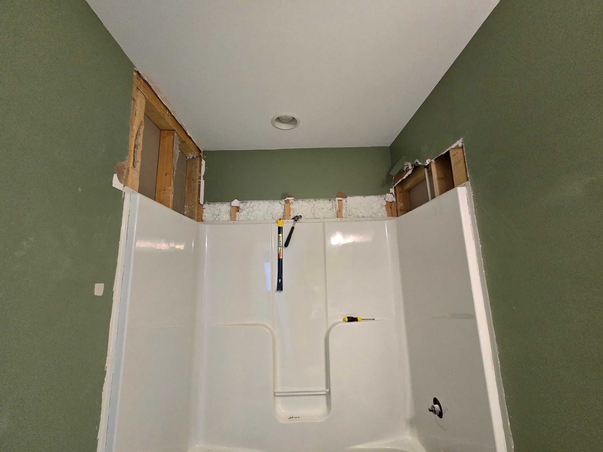 The alcove shower tub with the anti-faucet side clear of drywall up to the ceiling; the other two sides have cuts from my explorations but need taken up to the celing.