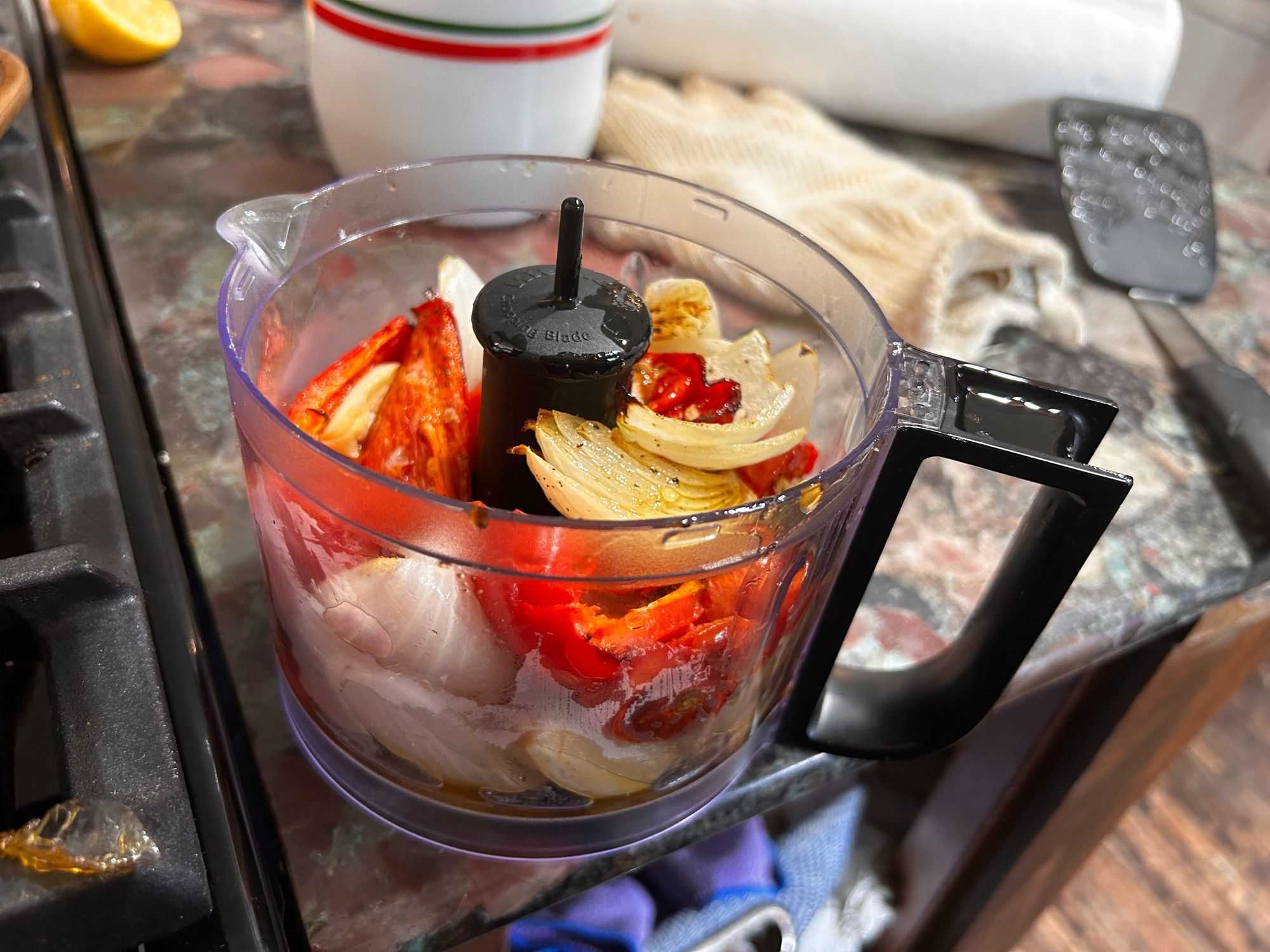 onions, red peppers, and garlic are placed in a bowl of a food processor.