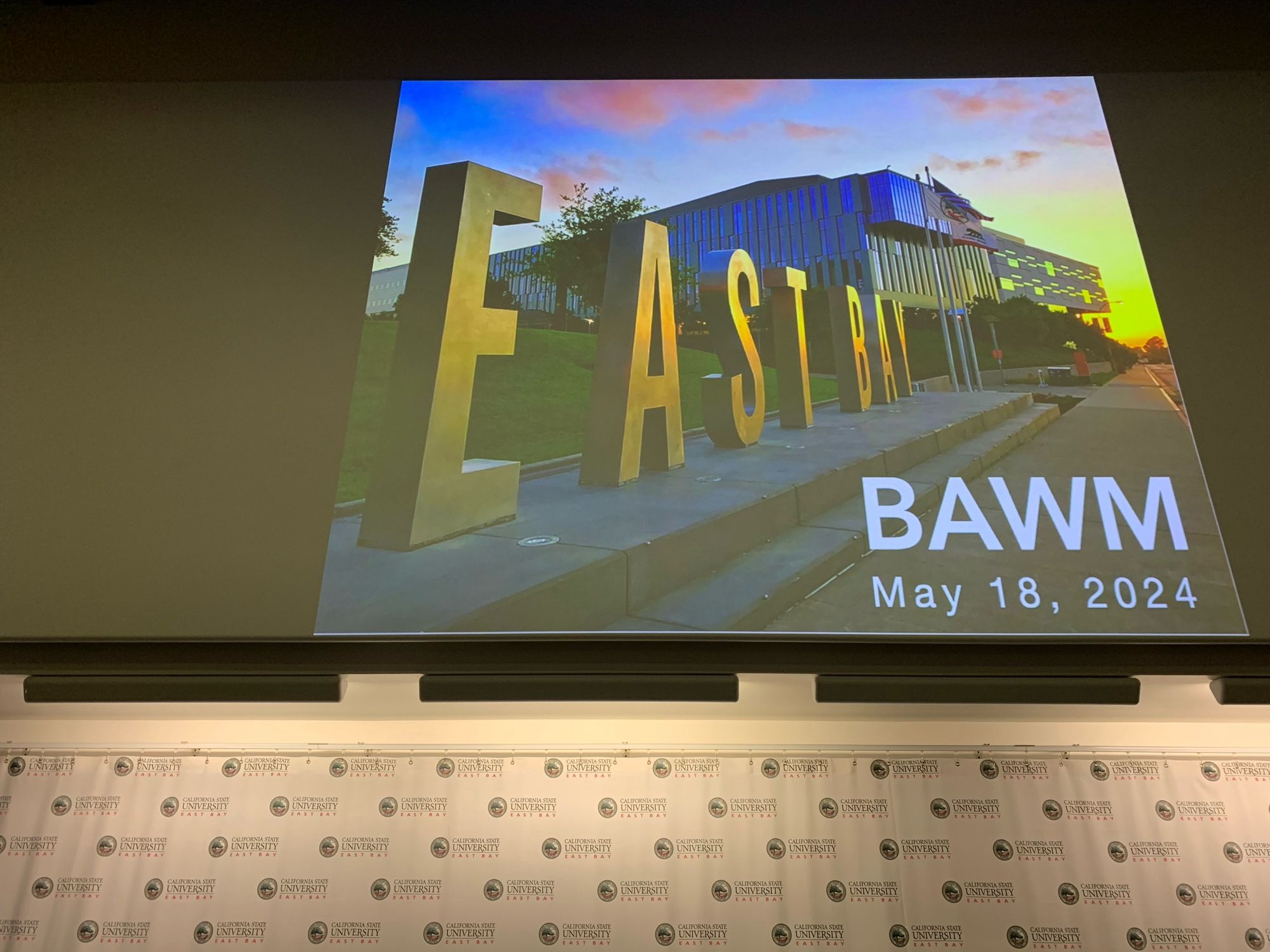 Welcome image of the Cal State East Bay entryway made by meeting organizer,  Prof Maria Elena Gallegos. Block letters in bottom right announce BAWM May 18 2024