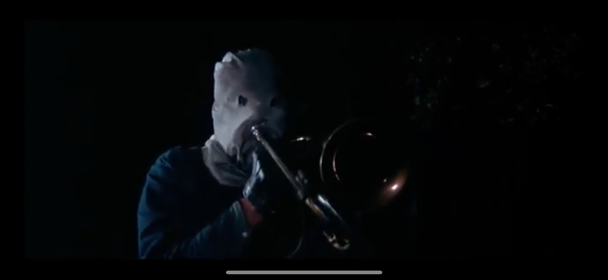 Screenshot from The Town That Dreaded Sundown (1976) of the masked killer wielding a trombone with a knife affixed to it.