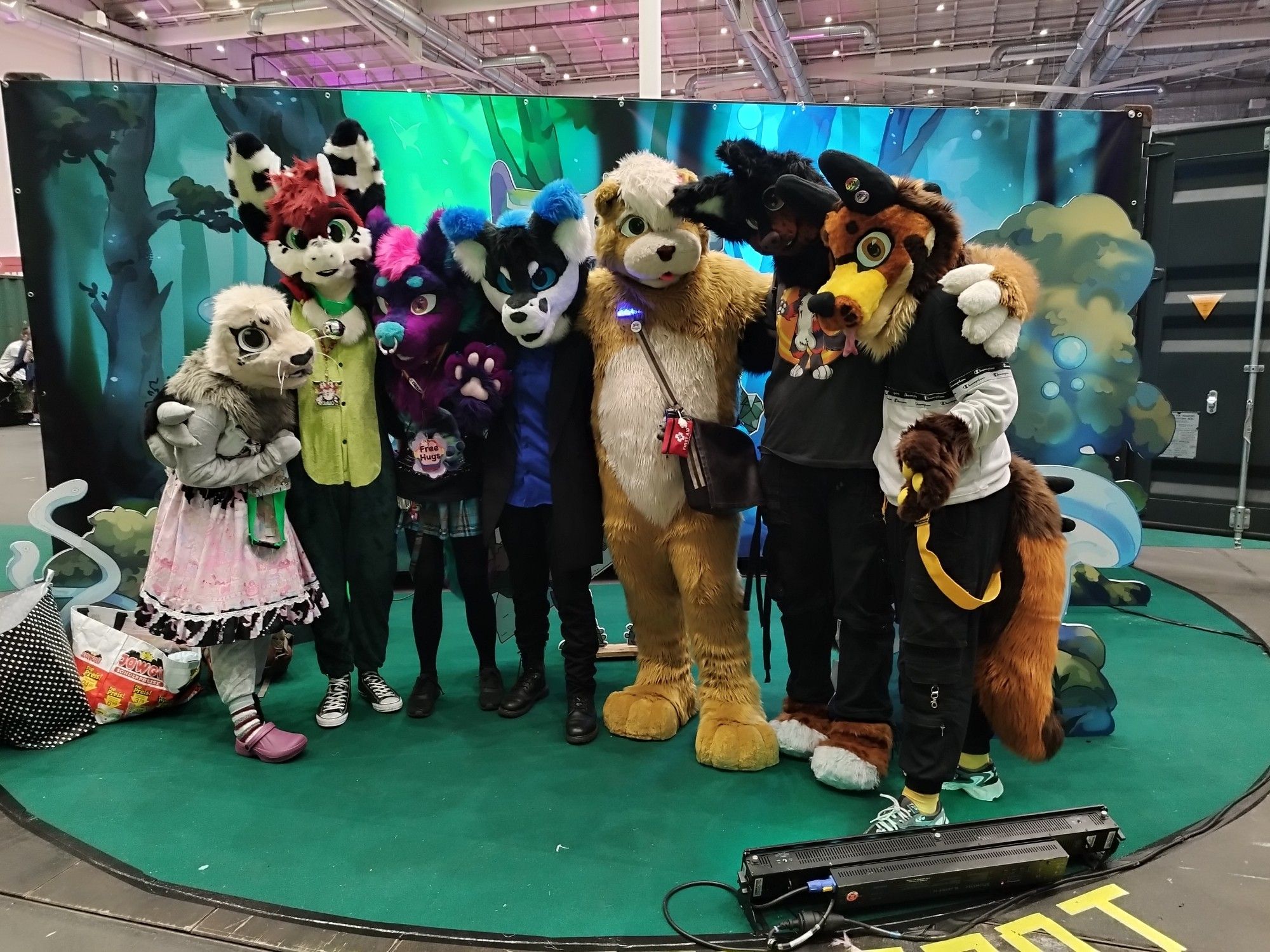 A bunch of Fursuiter are standing in a Grouppicture with an Anime-Like Background