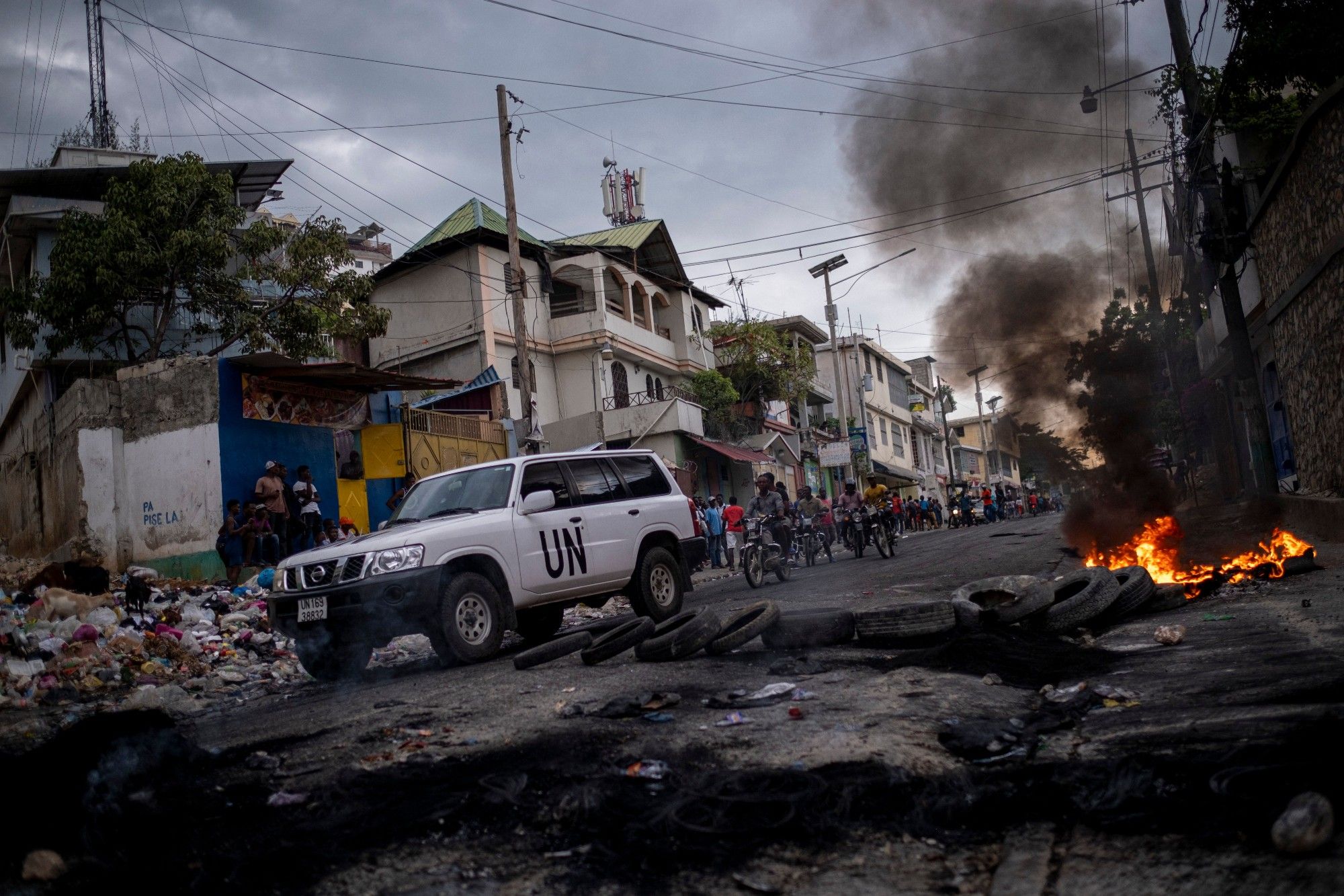 A UN vehicle drives past a barricade of burning tires during a demonstration against high prices and fuel shortages in Port-au-Prince, Haiti, Oct. 21, 2021.