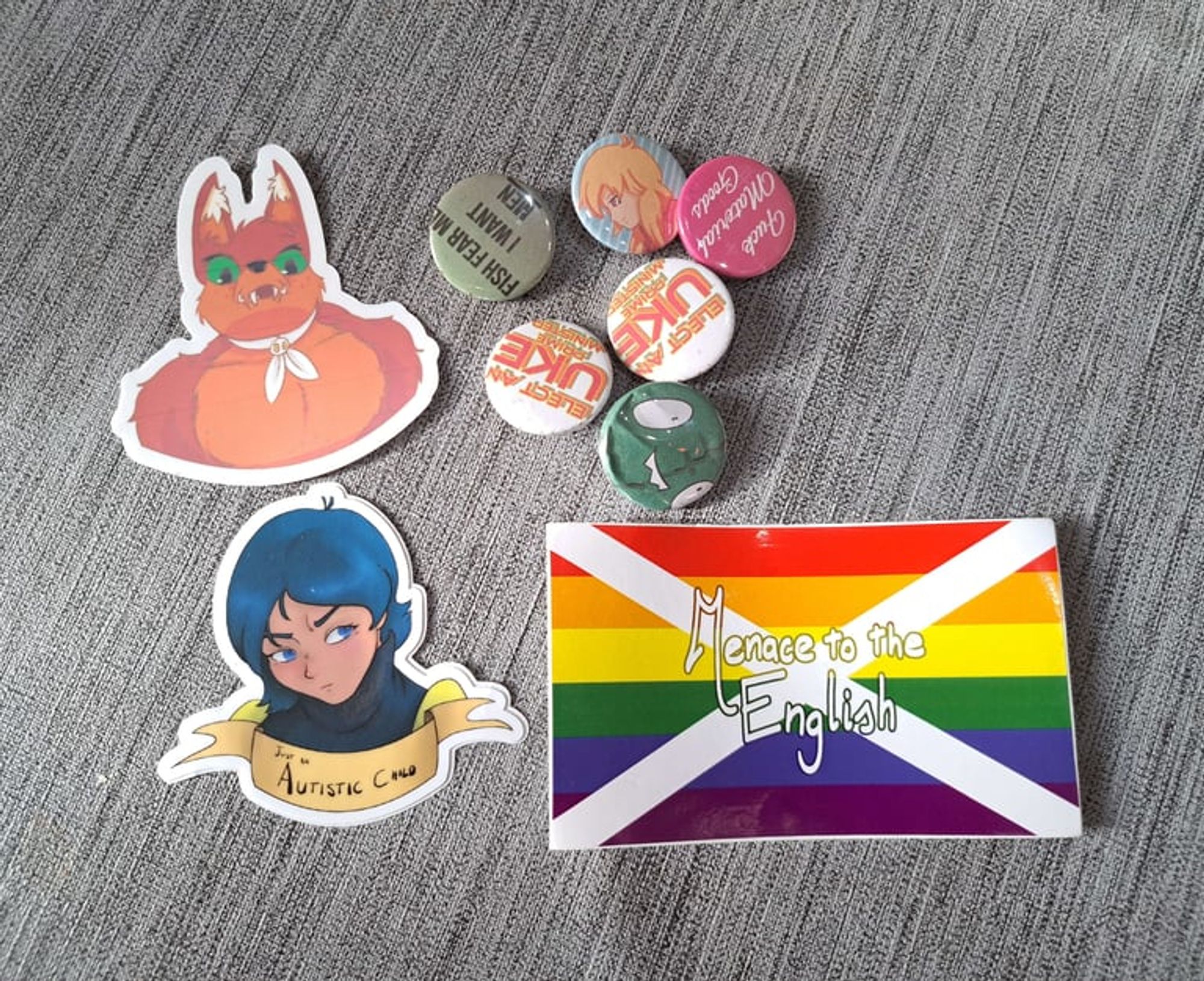 A bundle of stickers and button badges with slight damage or print issues