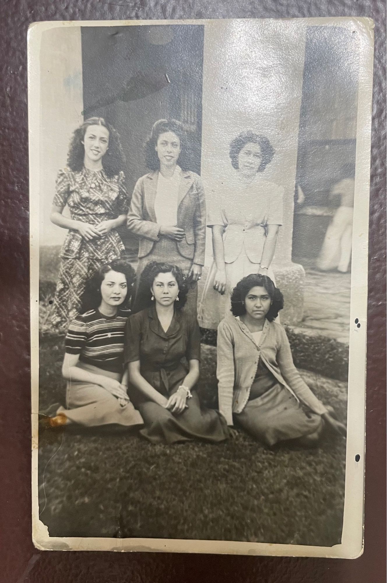 Black and white photo, dated 1945. The curly-haired girl, aged 19, poses outdoors with five other young women in what appears to be a courtyard. We have no idea who or where these people are.