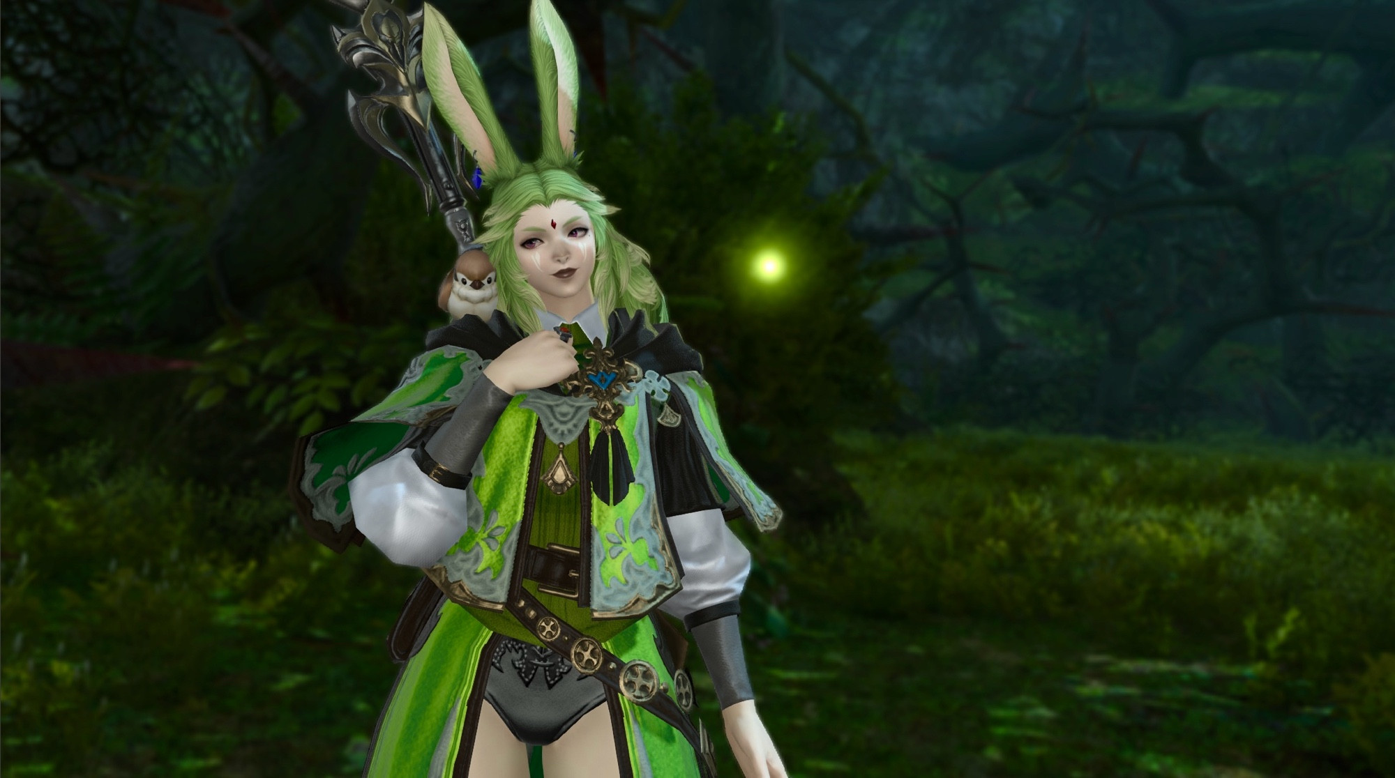 A screenshot of a green haired Viera Warrior of Light from Final Fantasy 14. She is standing in a dimly lit forest with a single firefly hovering next to her. She is wearing layered fantasy clothes with a metallic green outer coat, posing with her hand on her chest. Her head is slightly tilted to the left and she is looking at a small brown road sparrow that is perched on her shoulder. She has a pleasant expression on her face.