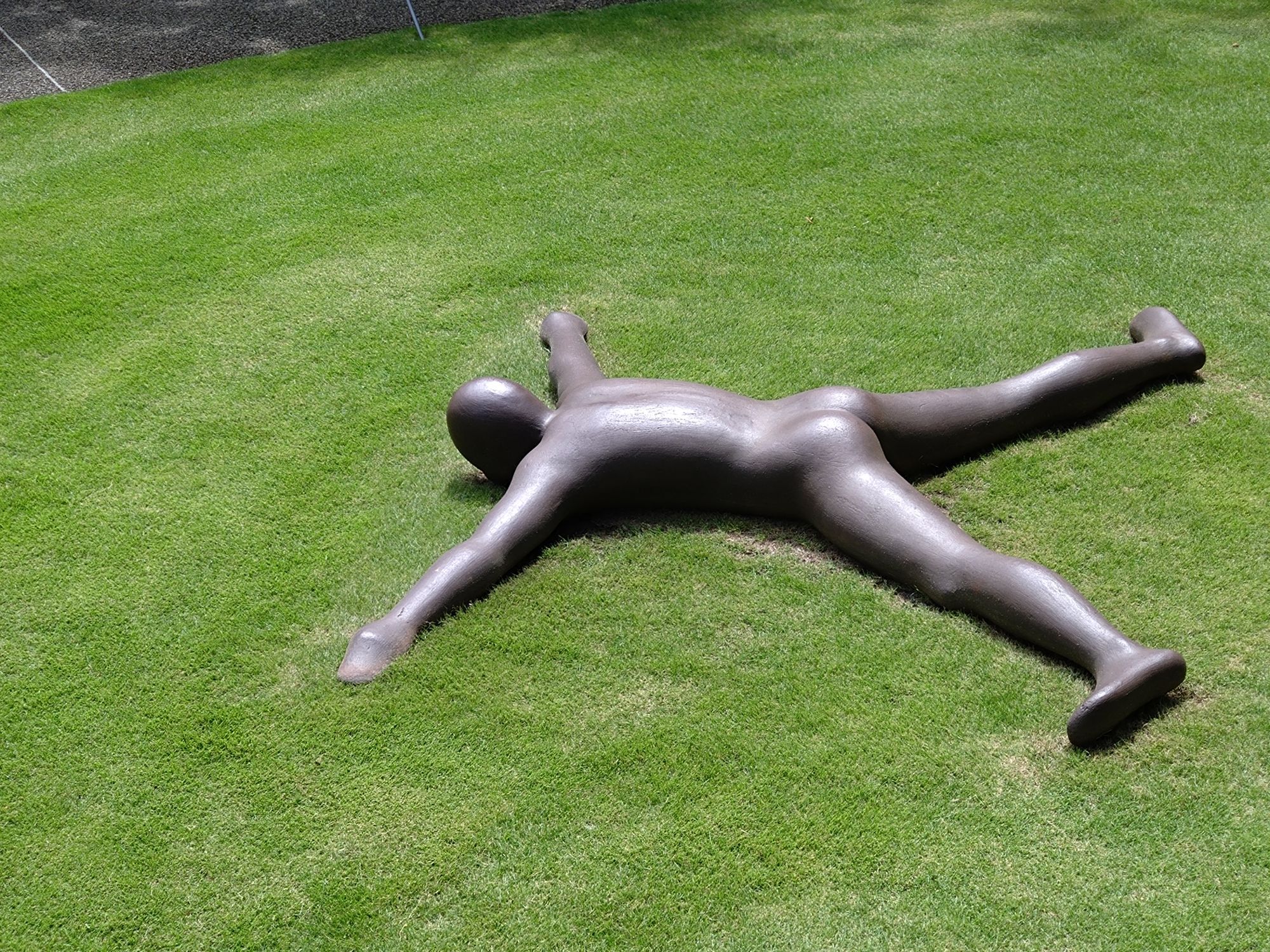 A sculpture of a man lying on the floor completelysprawled out